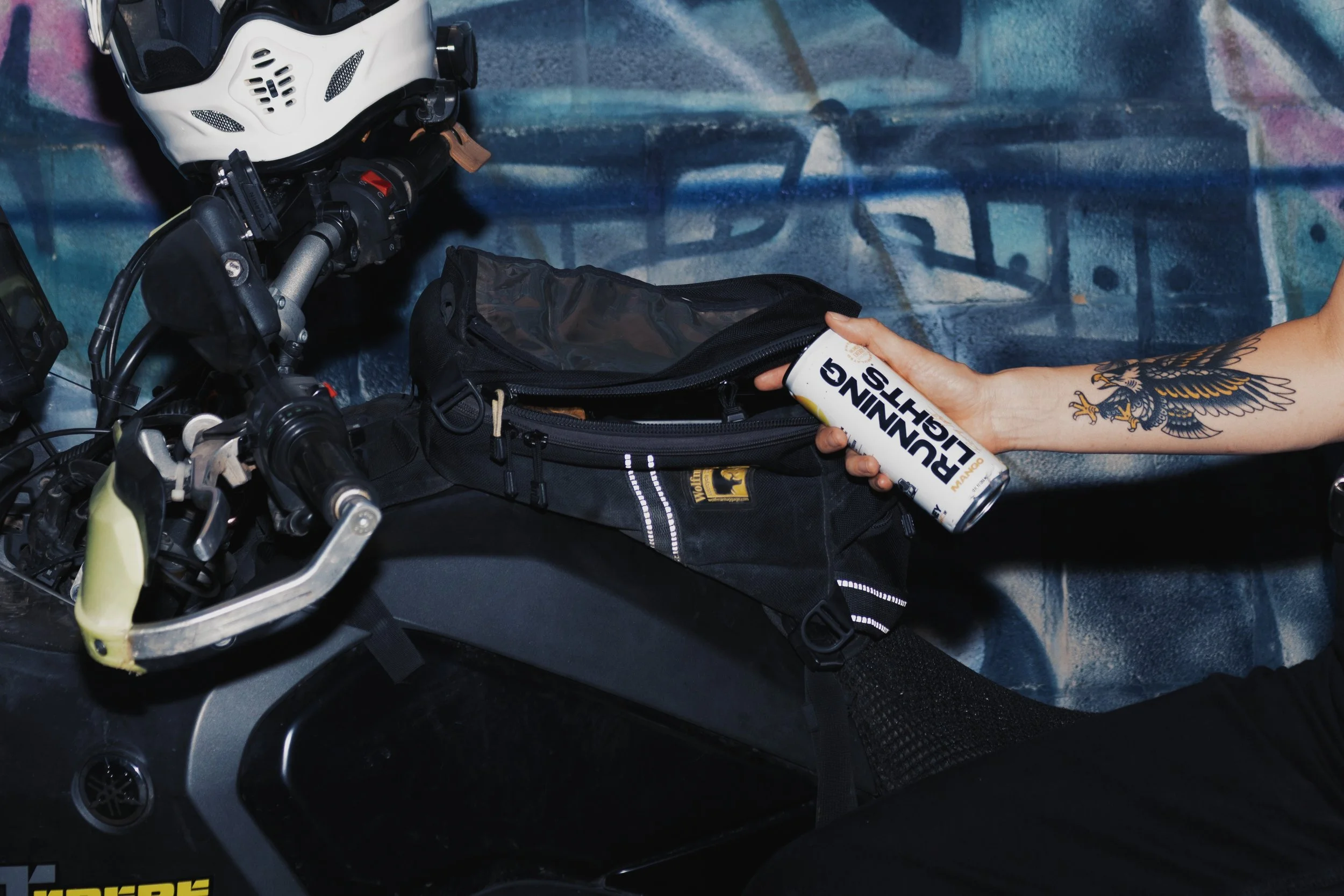 Close up of woman holding a can of Running Lights in front of a motorcycle