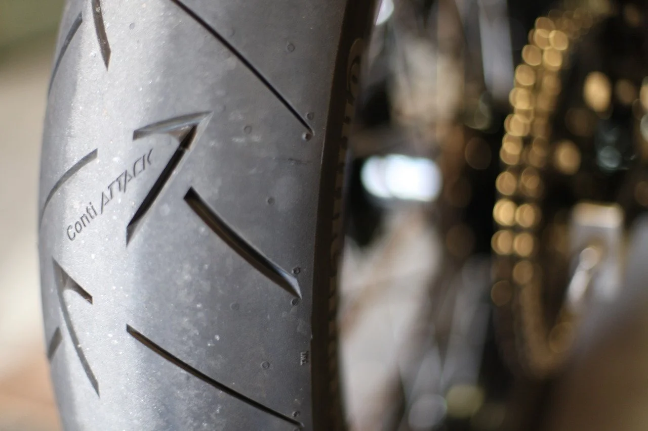 Close-up of a Continental motorcycle tire showing tread pattern and a small section of the chain.