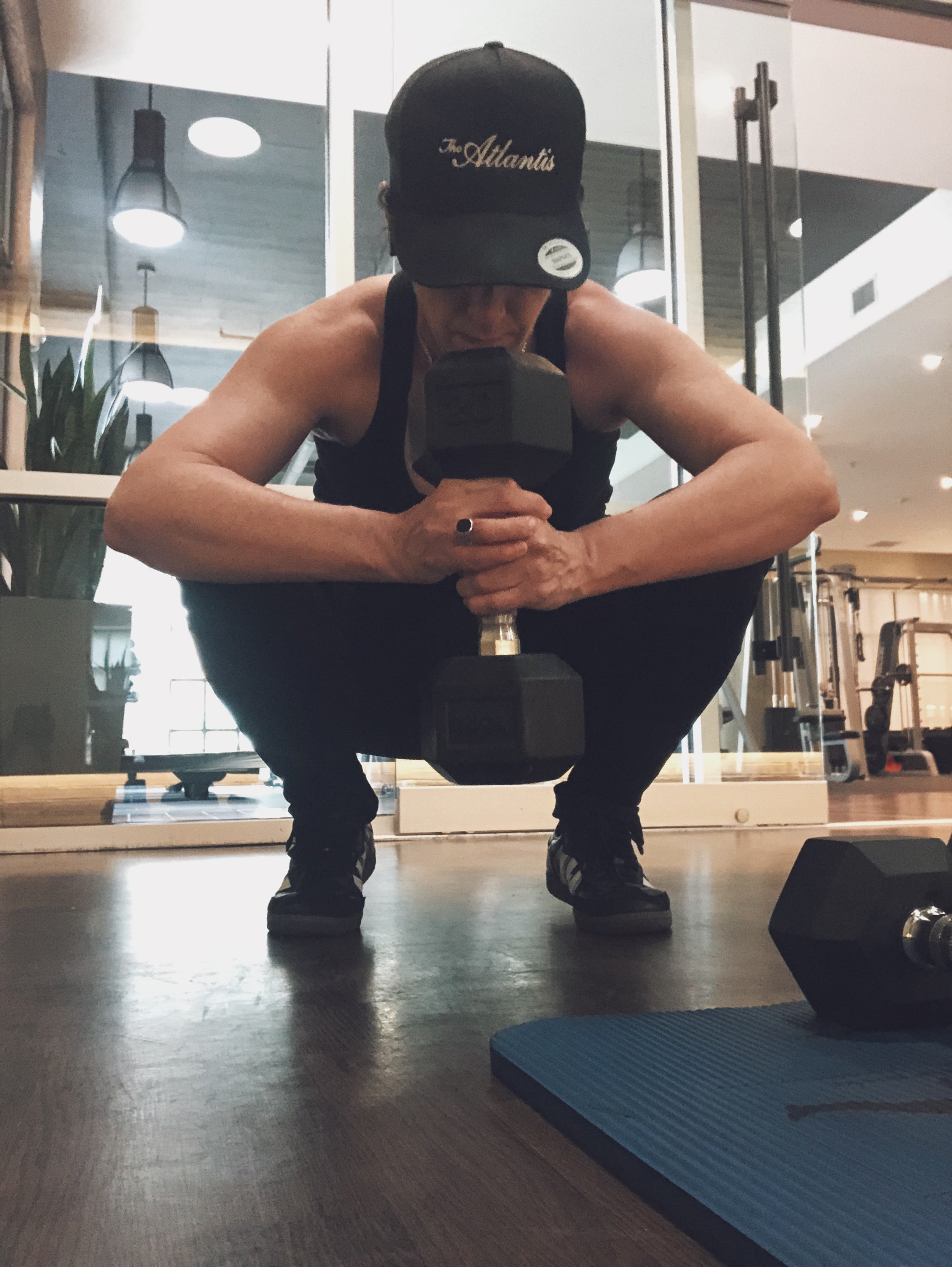 A person holding a York Barbell dumbbell weight doing squats.