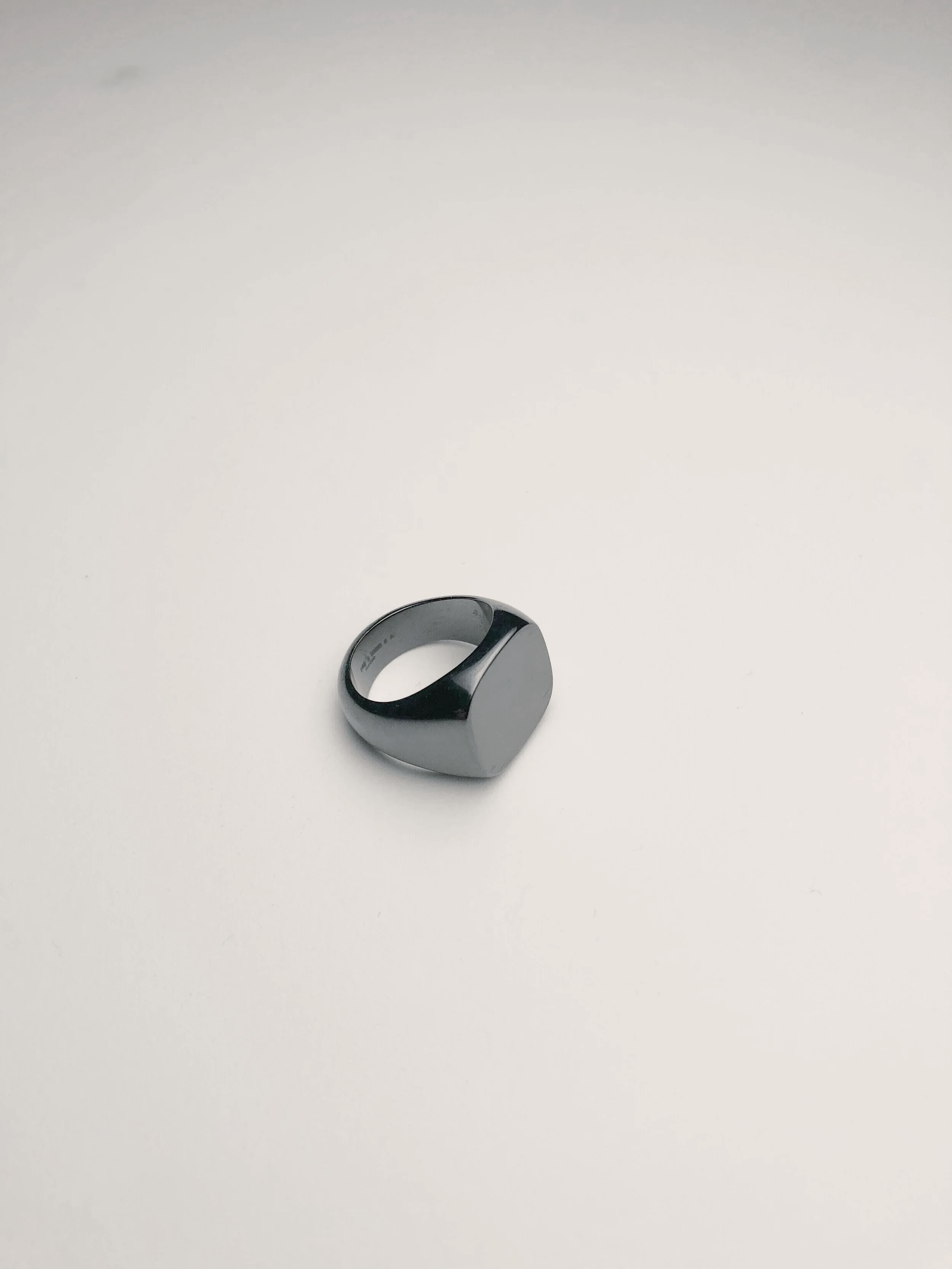 A silver and black ring with a smooth, matte finish, placed on a plain white surface.