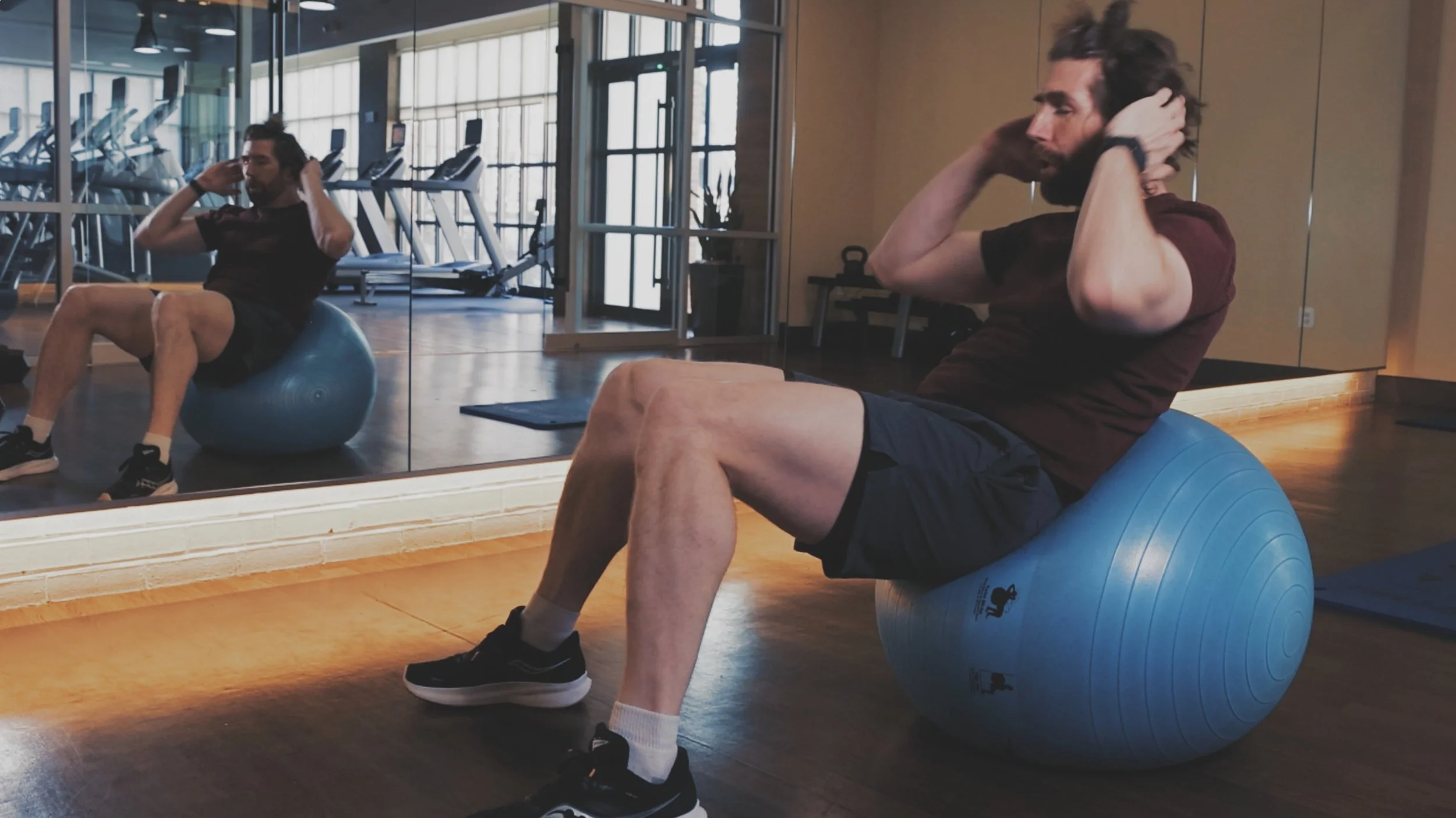A man exercising with a Prism Fitness blue workout ball.