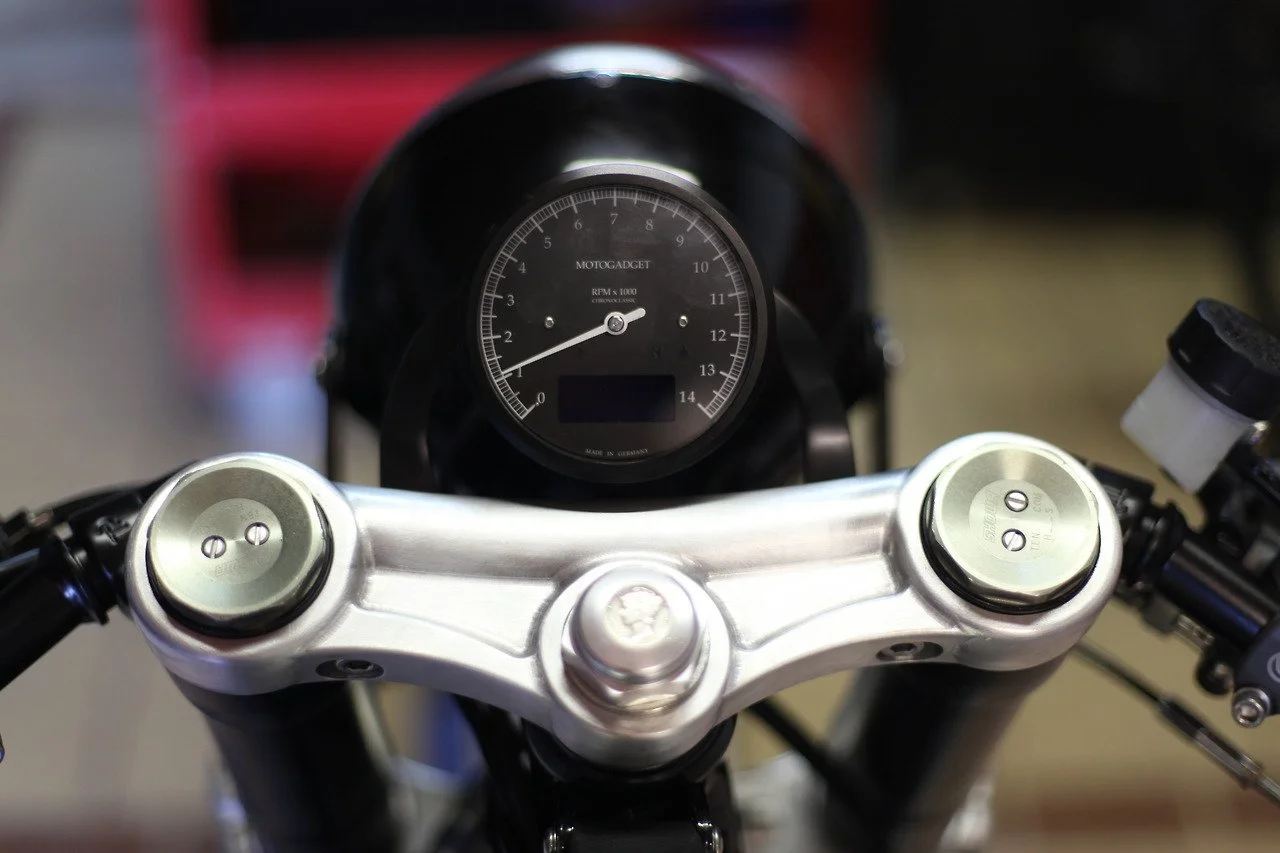 Close-up view of a motorcycle's handlebars and Motogadget tachometer above the triple tree..