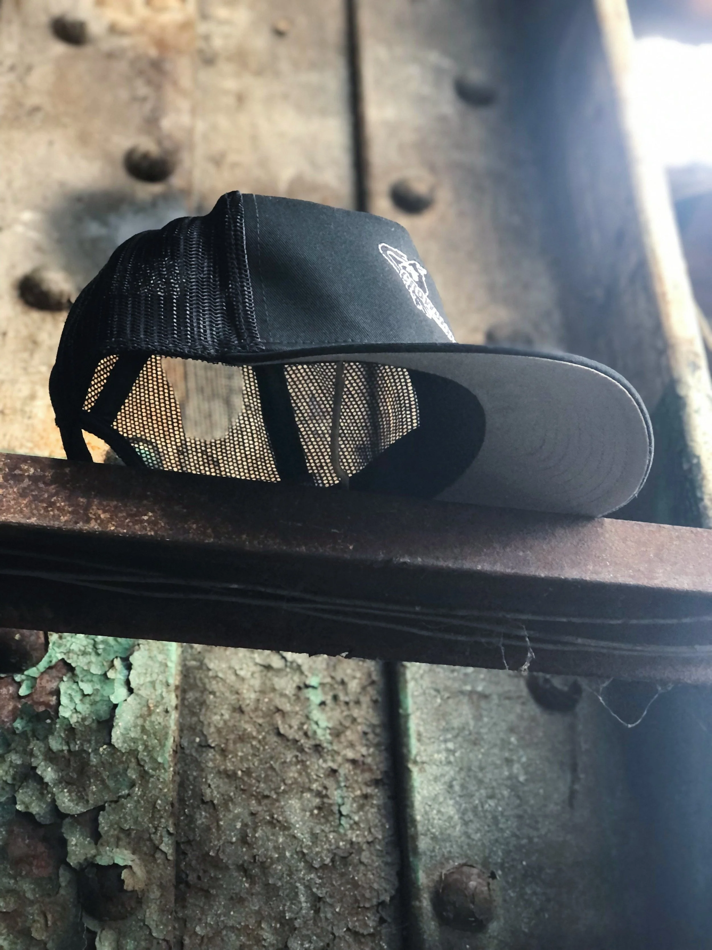 A black trucker hat with the Crowbar music venue logo shot from below on an industrial rail and metal background.