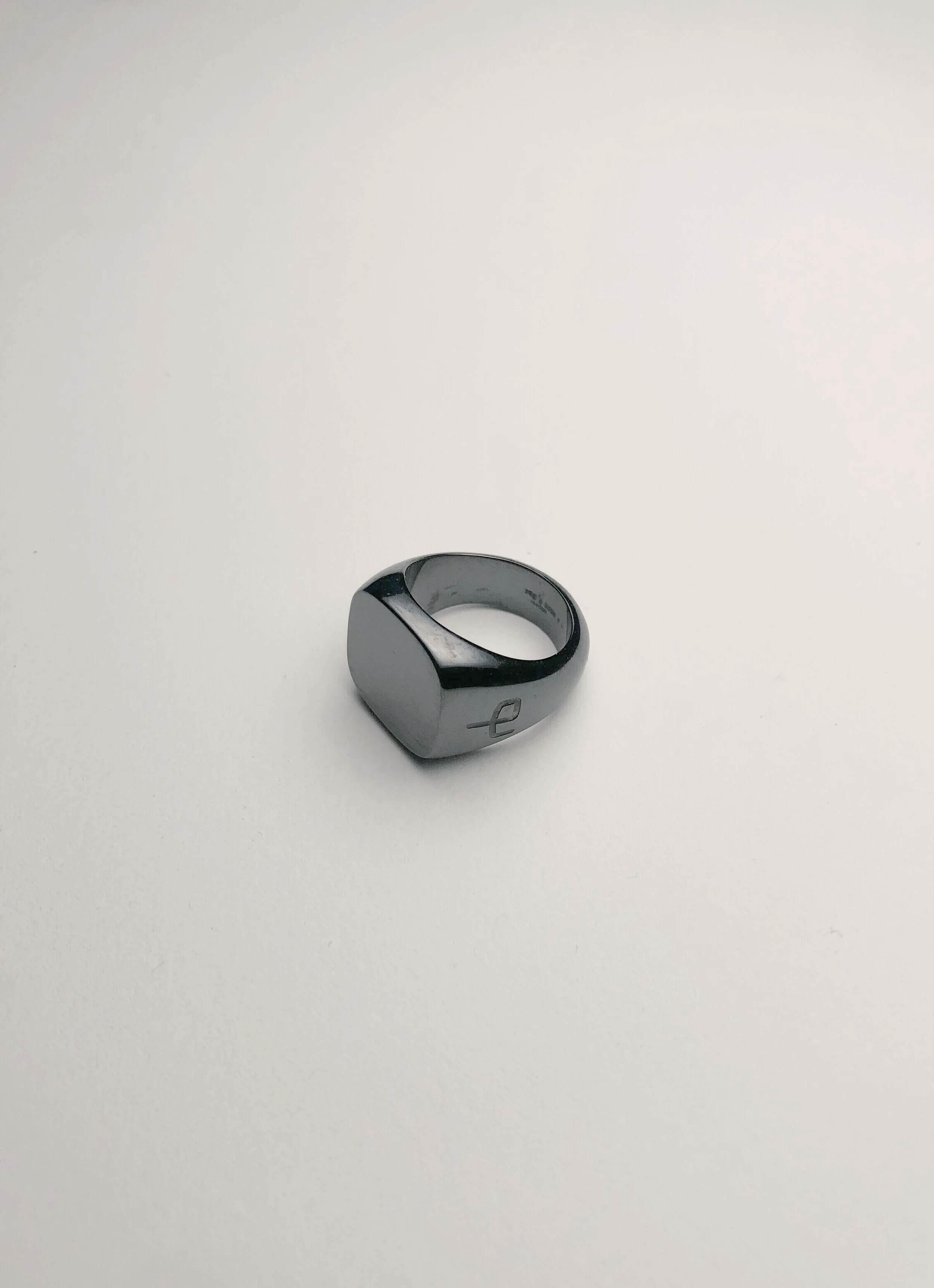 A metallic ring with a cross symbol engraved on it, placed on a white surface.