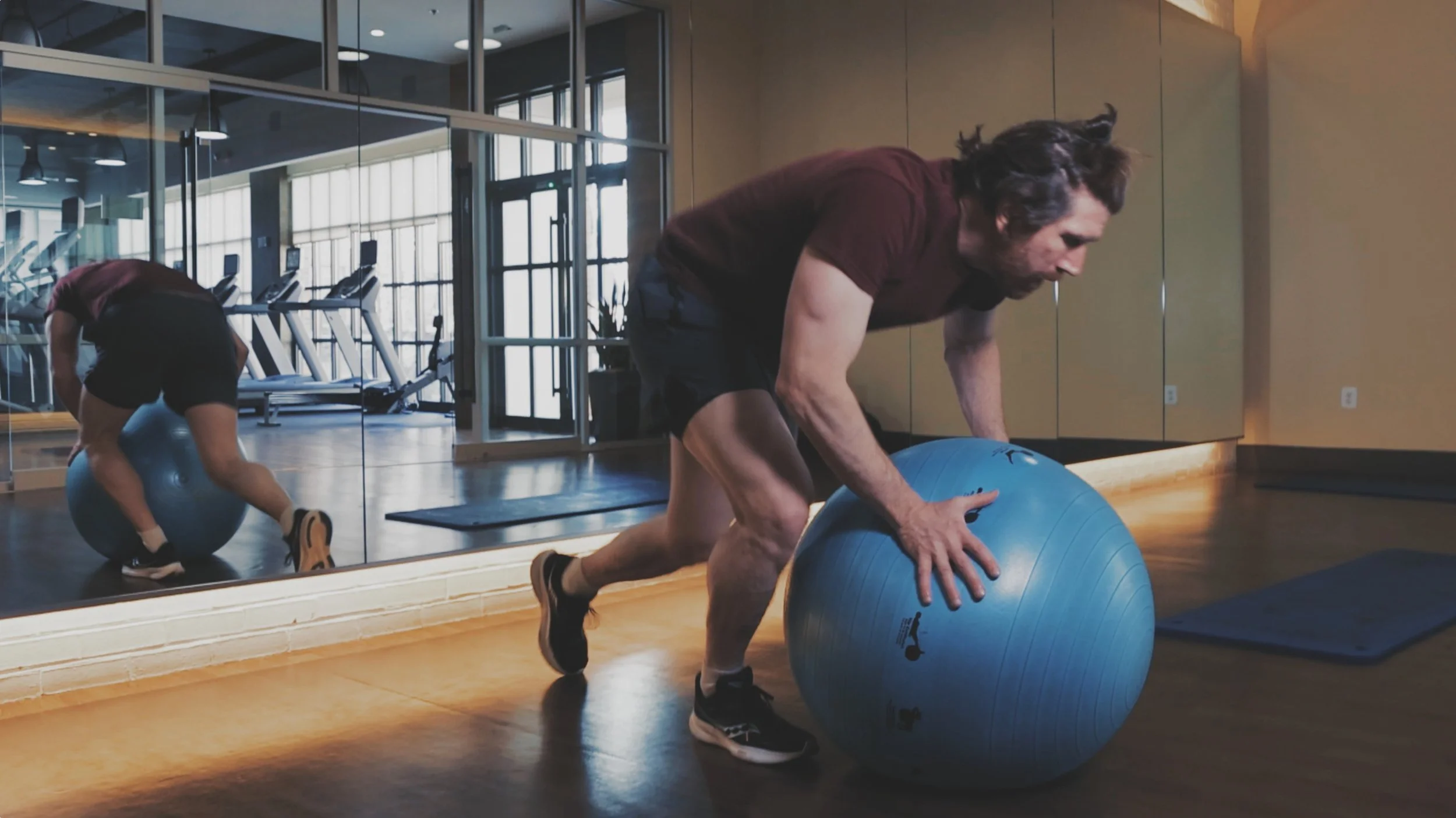 A man exercising with a Prism Fitness blue workout ball.