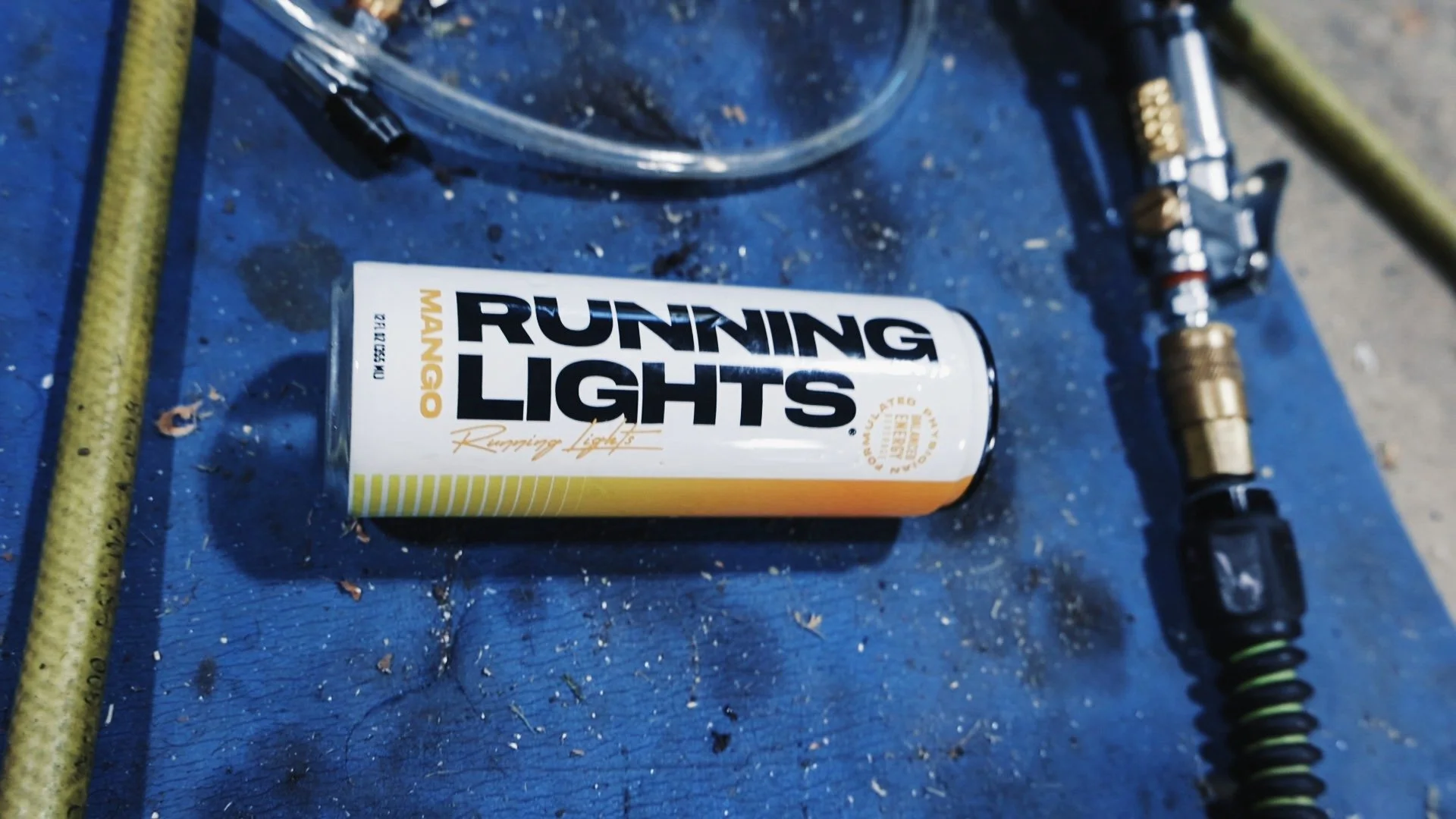 Flat lay of Running Lights Beverage on a mat with a compressor hose in a motorcycle shop