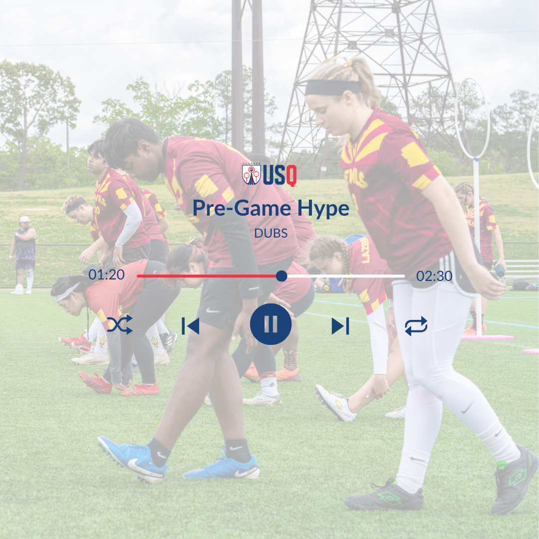 Young female and male athletes in red and yellow uniforms stretching on a soccer field during a pre-game warm-up, with spectators in the background.