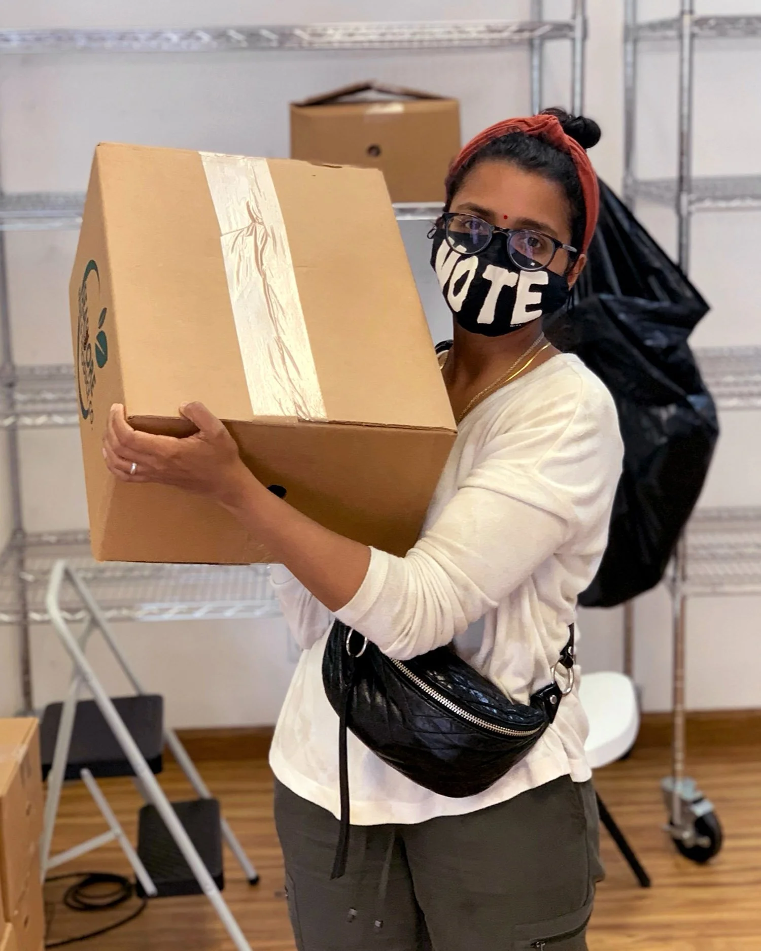 woman-holding-box-wearing-a-mask-saying-vote