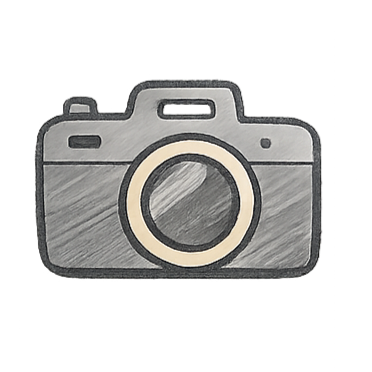 A landscape view of snow-capped mountains with a modern building in the foreground, surrounded by rolling hills and grassy terrain.