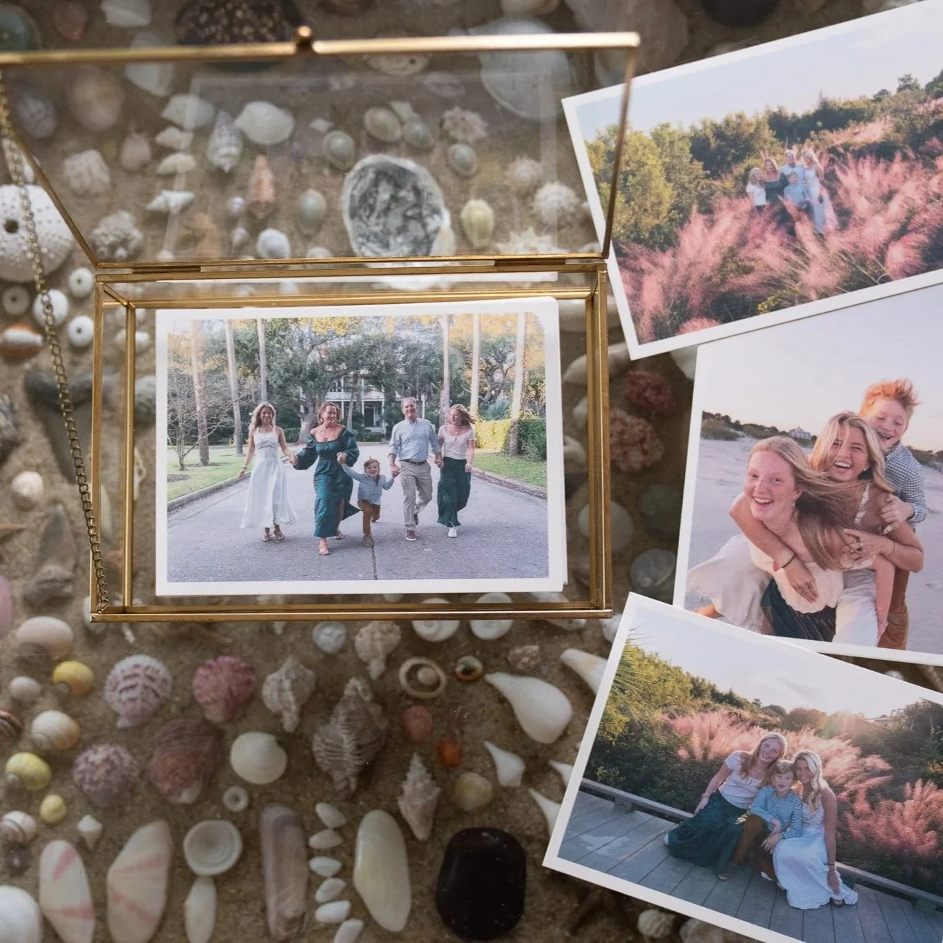 Beautiful glass and gold keepsake box filled with fine art prints from family photo session on a coastal coffee table