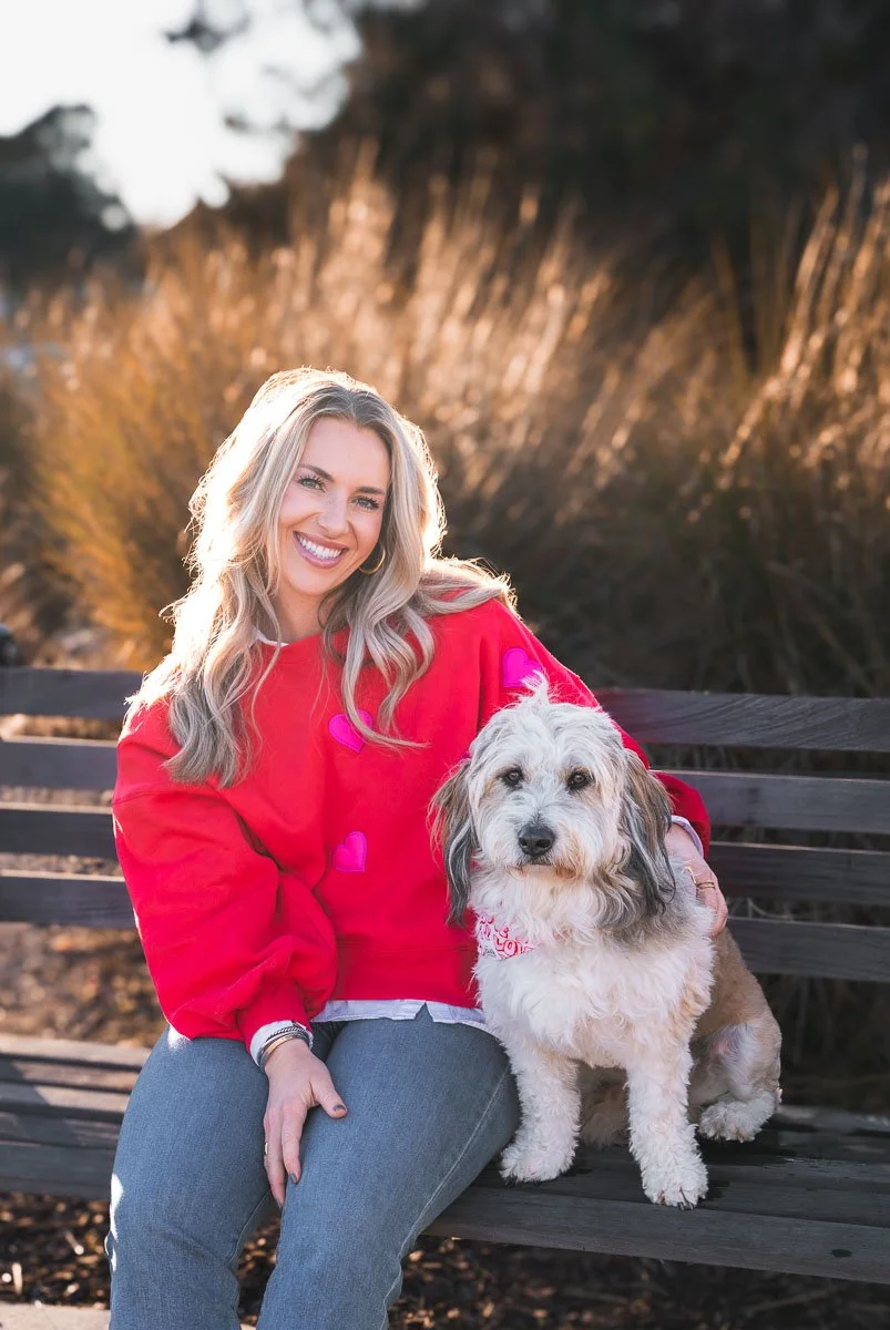 Young woman sits on a bench with her pup, posing for professional pet portraits in Charleston SC