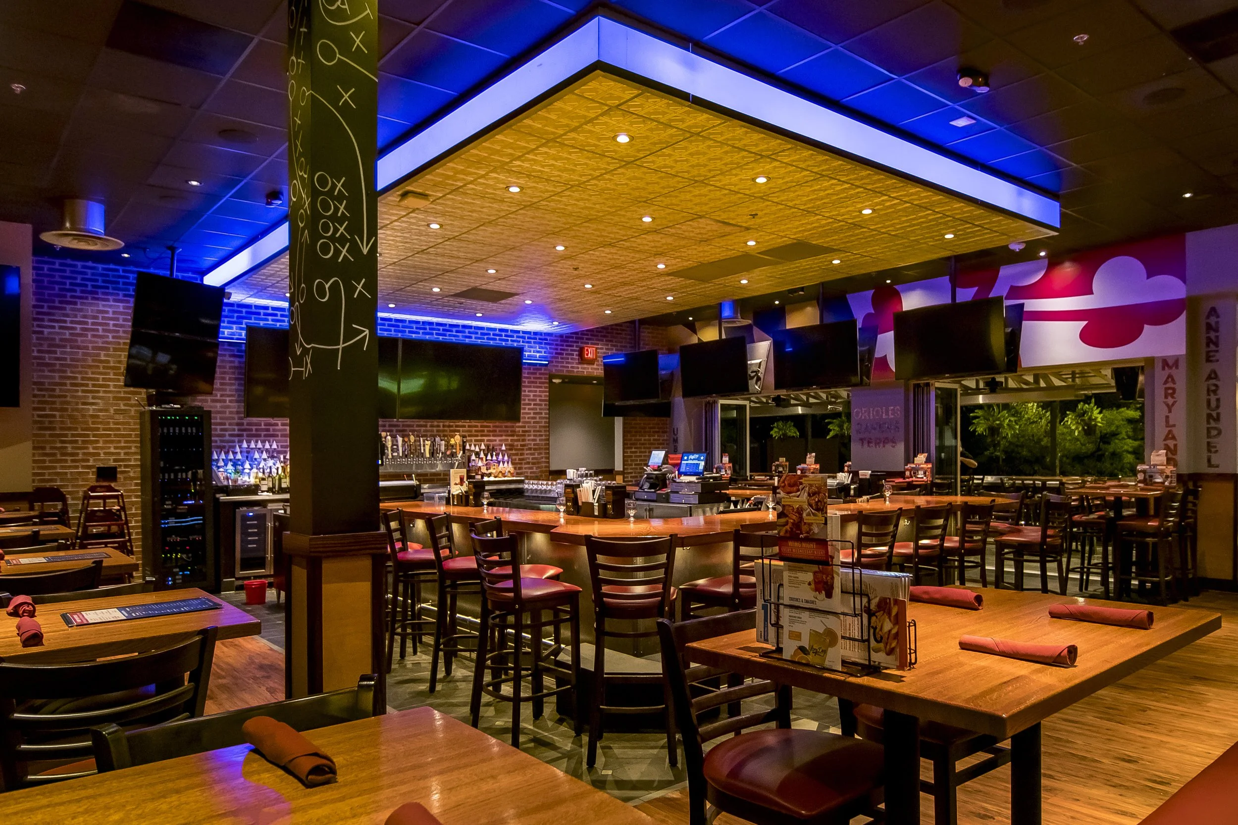 Neon Sports Bar with Bar Stools and Surrounding High Tops