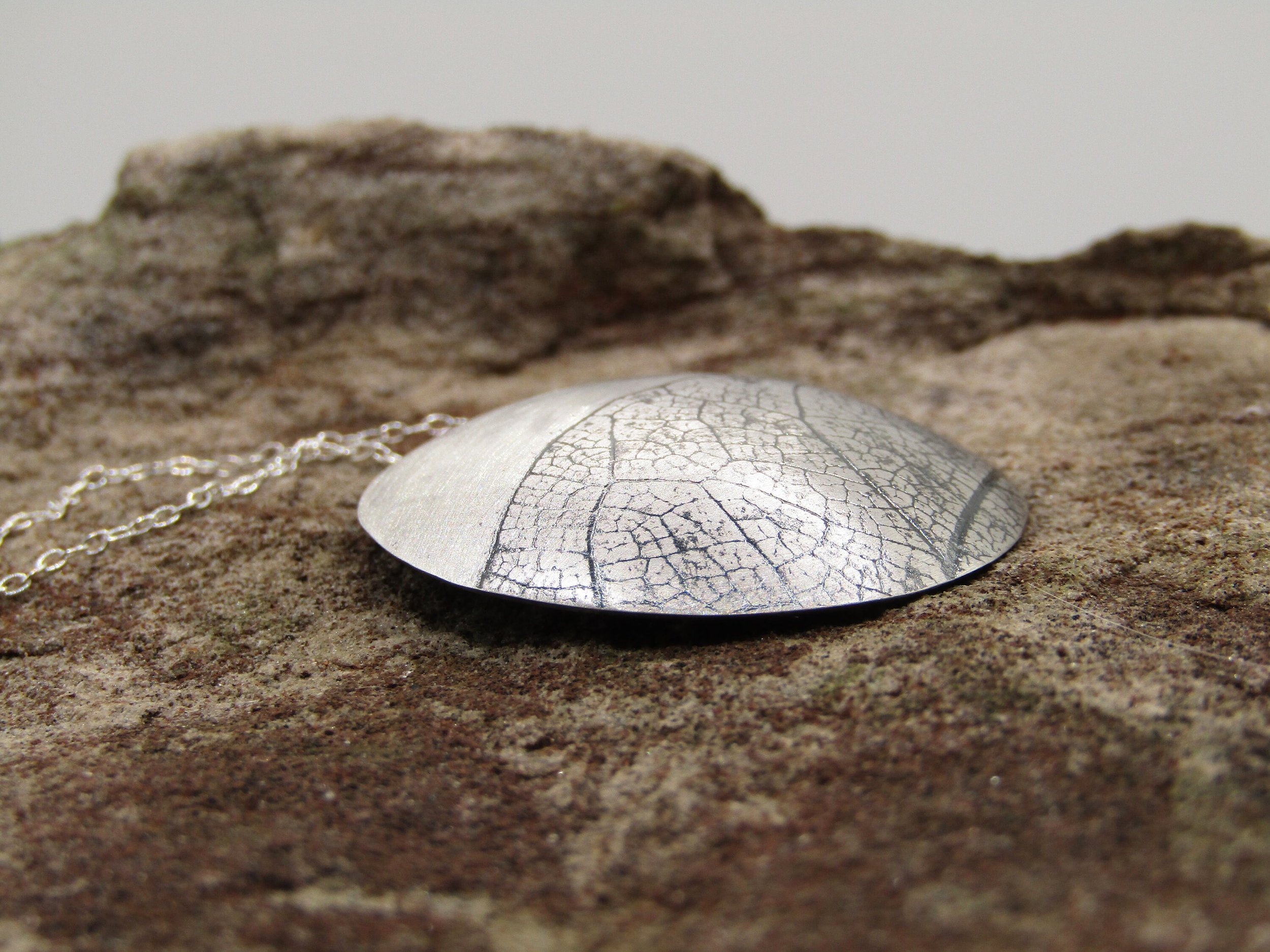 Silver domed pendant with leaf texture/J is for Jewellery