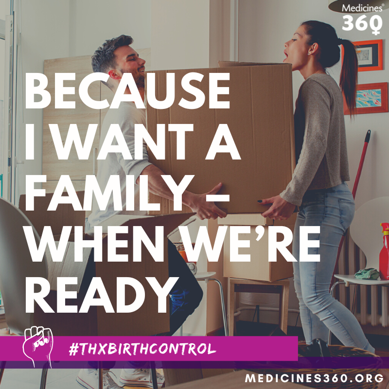 A woman and a man are moving boxes into a new home, with the woman handing a box to the man. There are framed pictures on the wall, a white radiator, and cleaning supplies visible in the background.