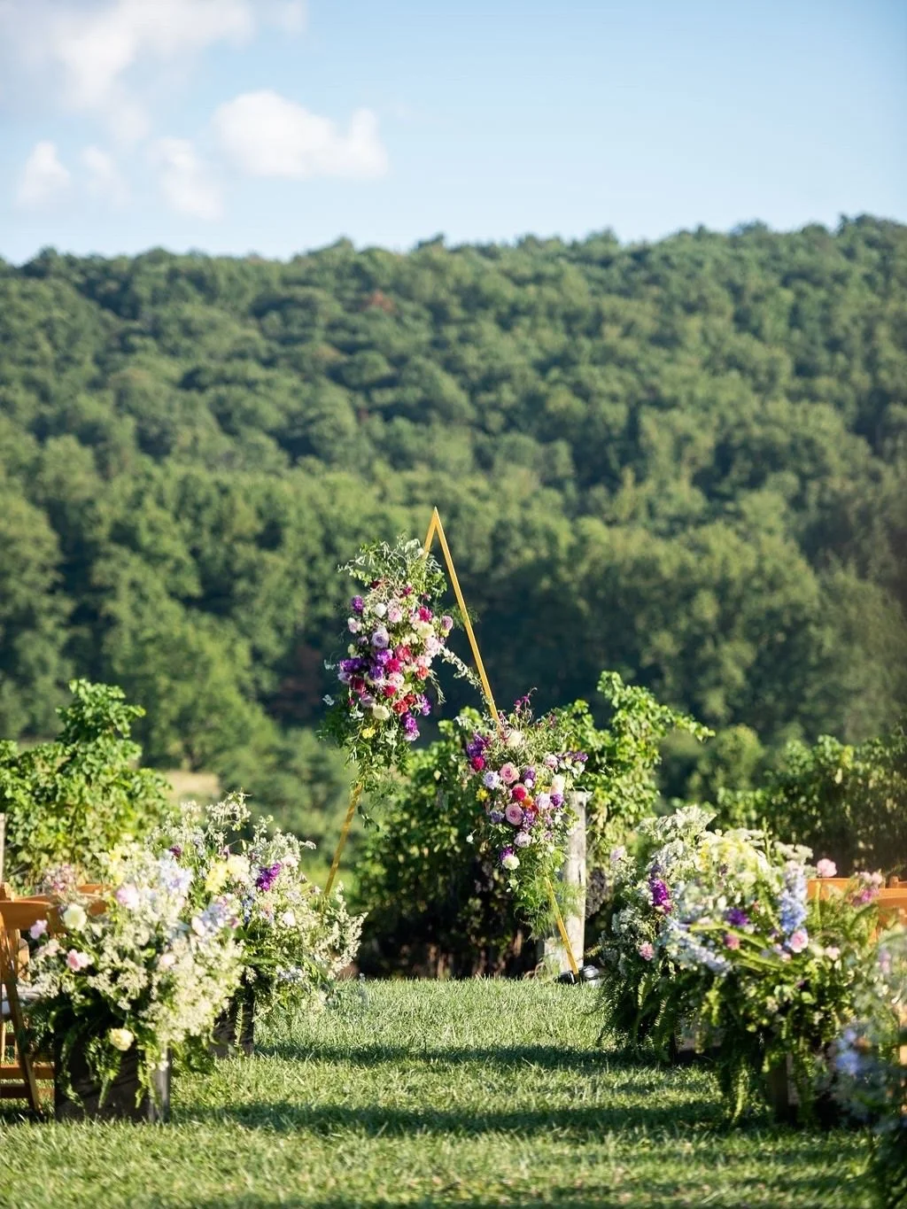 A vibrant Breaux Vineyards wedding in Purcellville, Virginia featuring a garden-inspired ceremony with colorful floral installations, asymmetrical arch design, and full-service luxury event production by Wildflower Hill Co. Perfect inspiration for vi