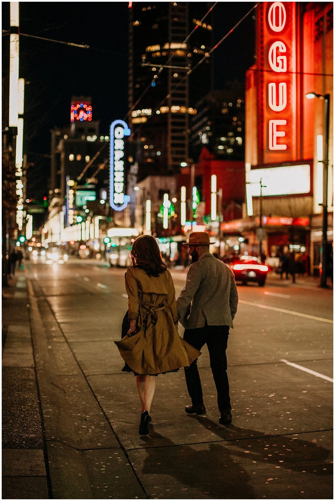 couple walking down granville strip neon lights engagement session