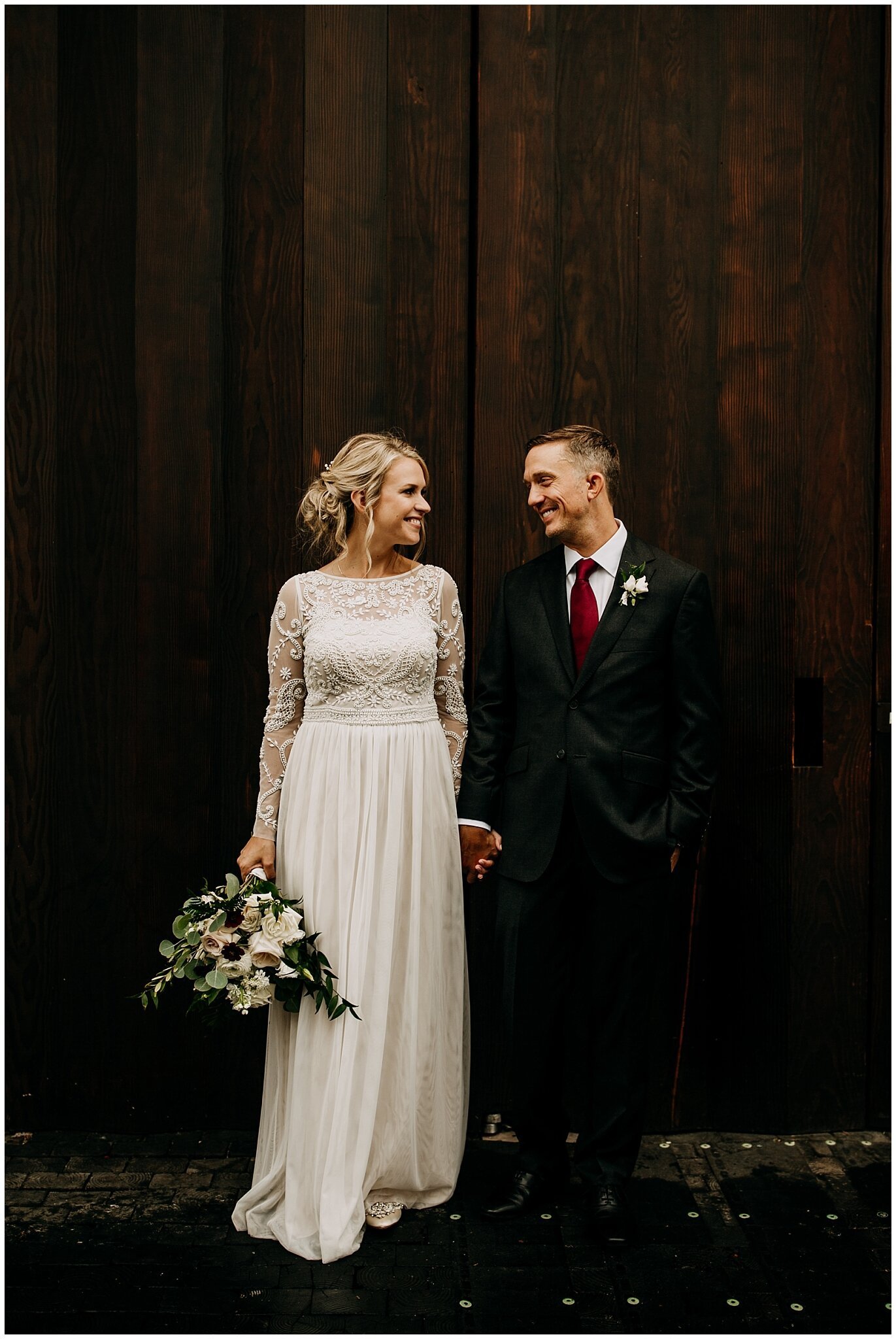 bride and groom portrait in front of settlement building doors