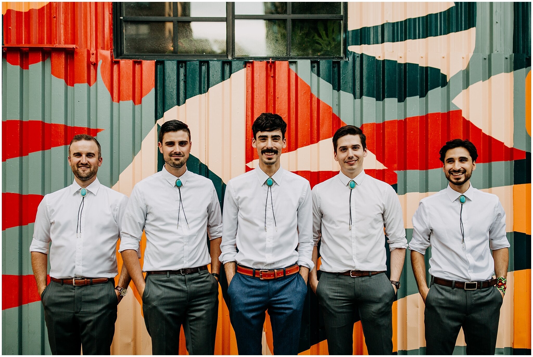 groom and groomsmen portrait in front of mural at ellis building wedding