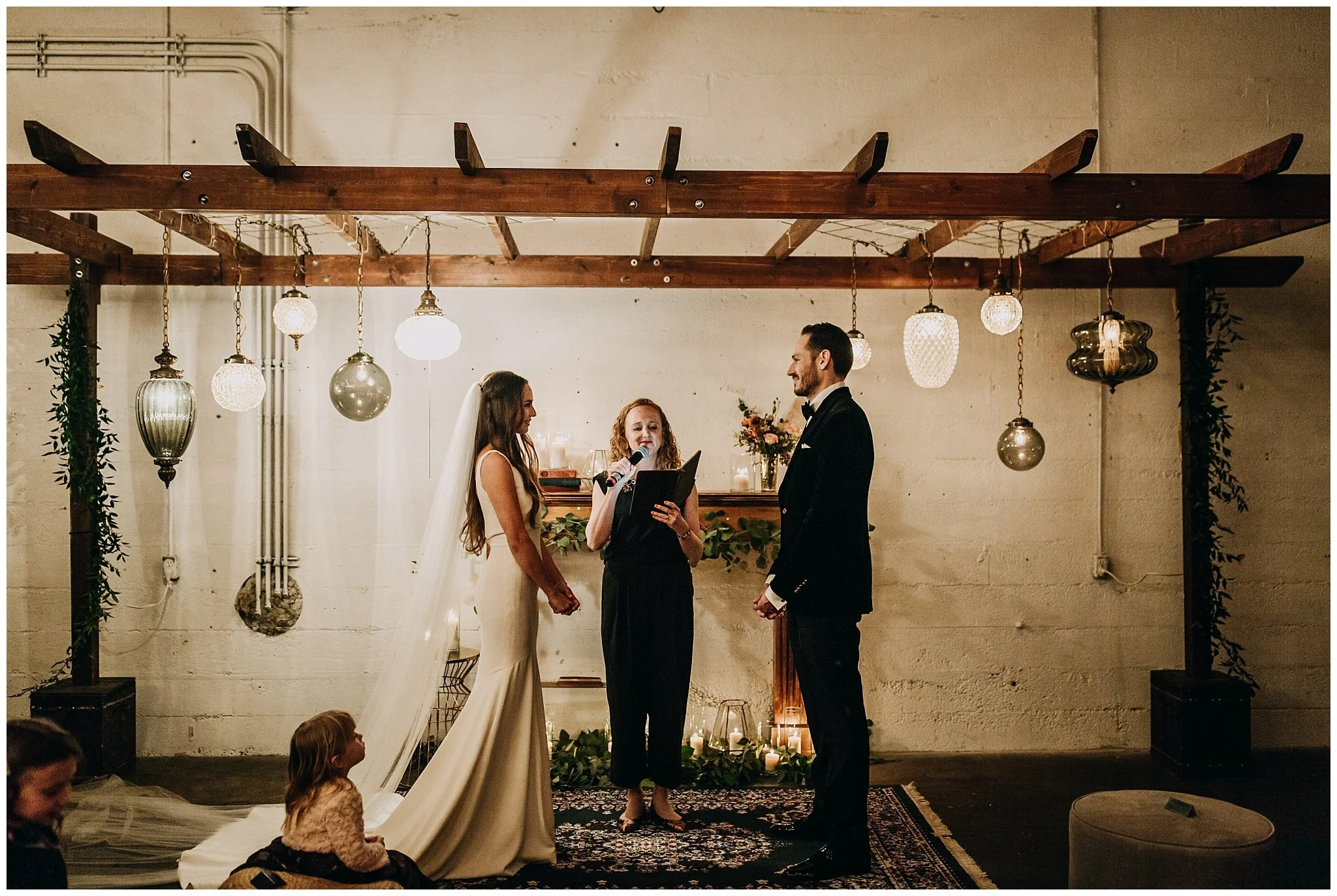 bride and groom standing at ceremony arch at settlement building wedding