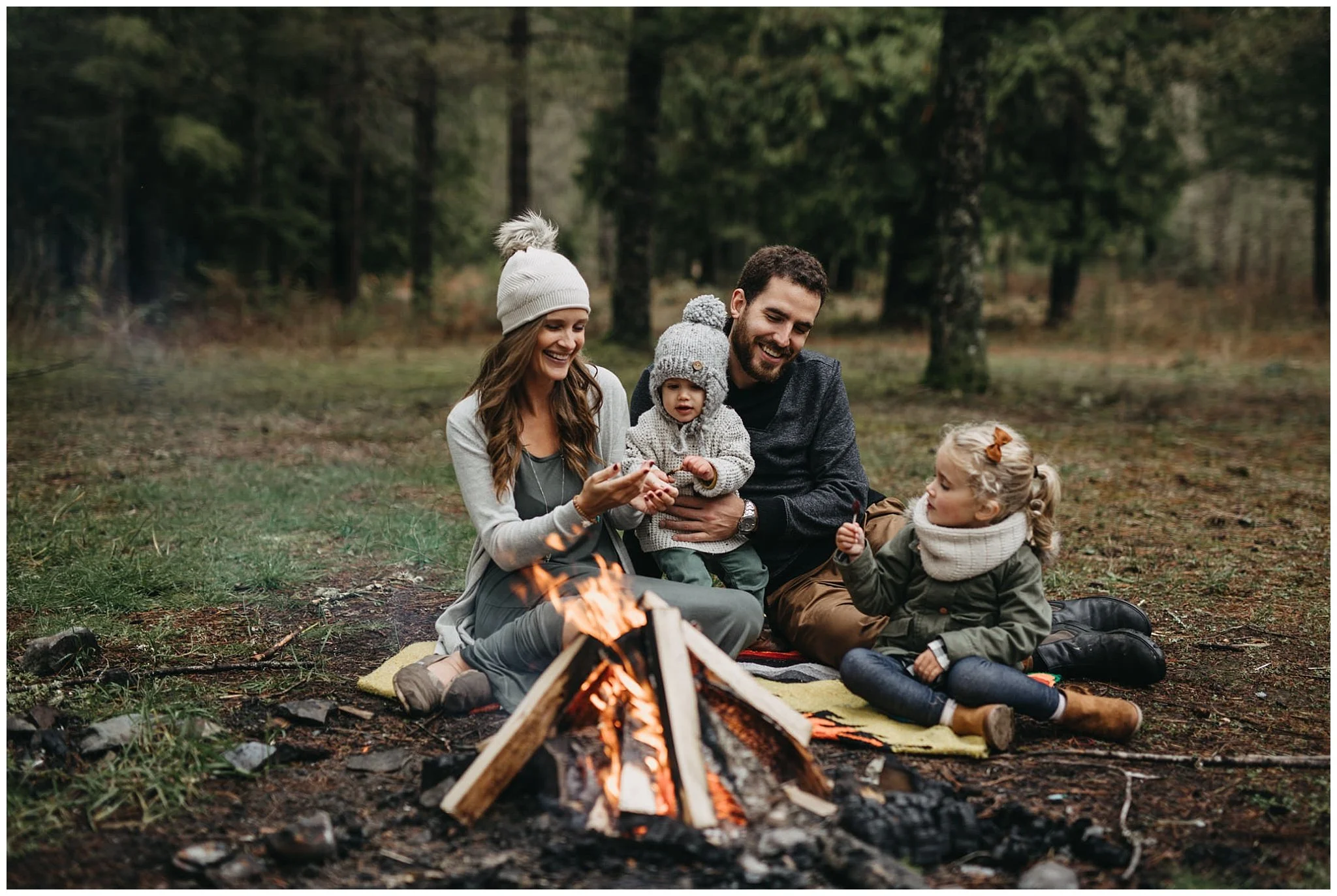 family sitting around campfire together on blanket chilliwack forest family photos