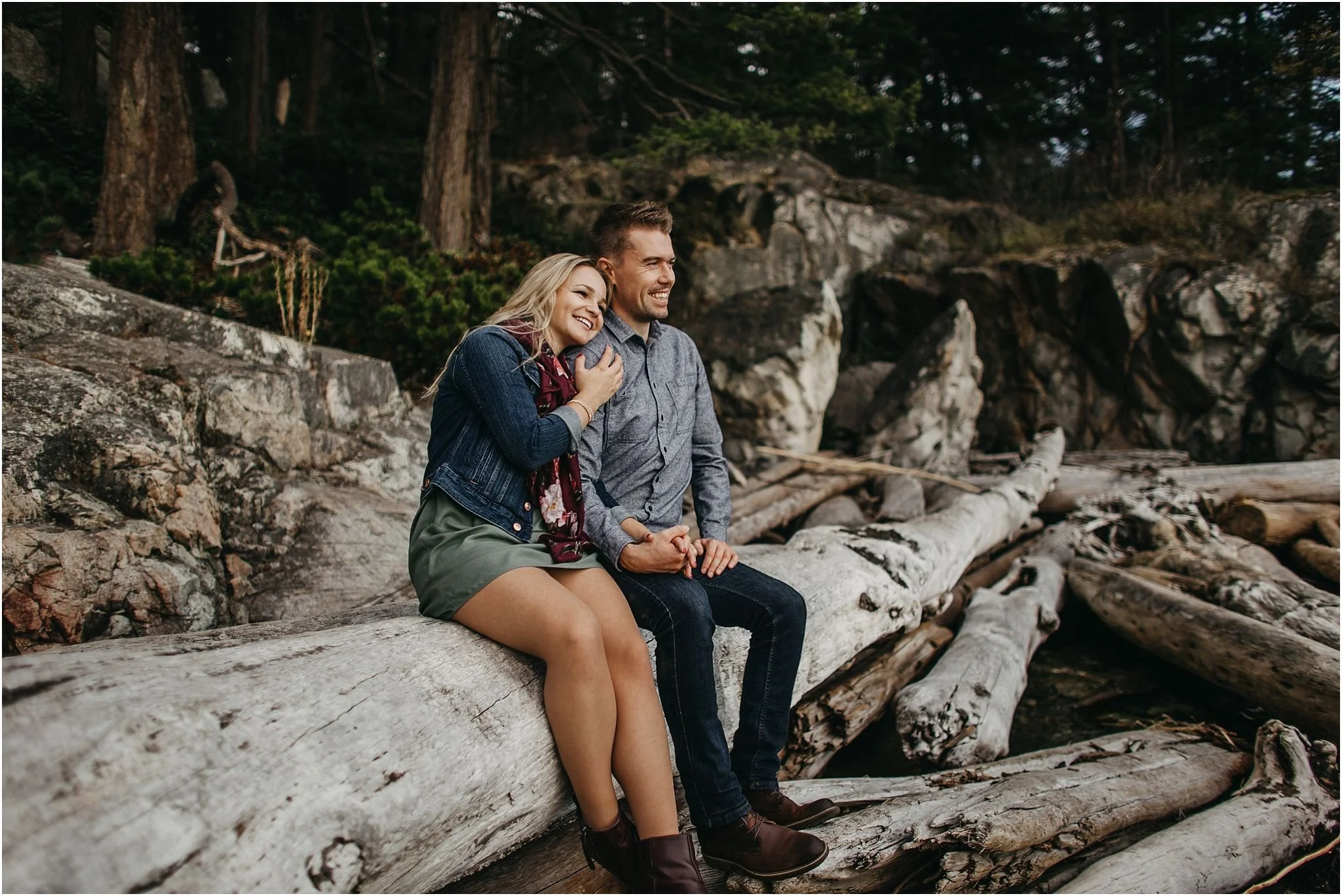 couple sitting on log at lighthouse park looking out at view