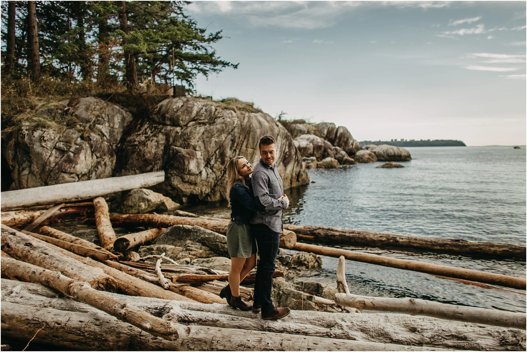 woman hugging man standing on logs ocean lighthouse park