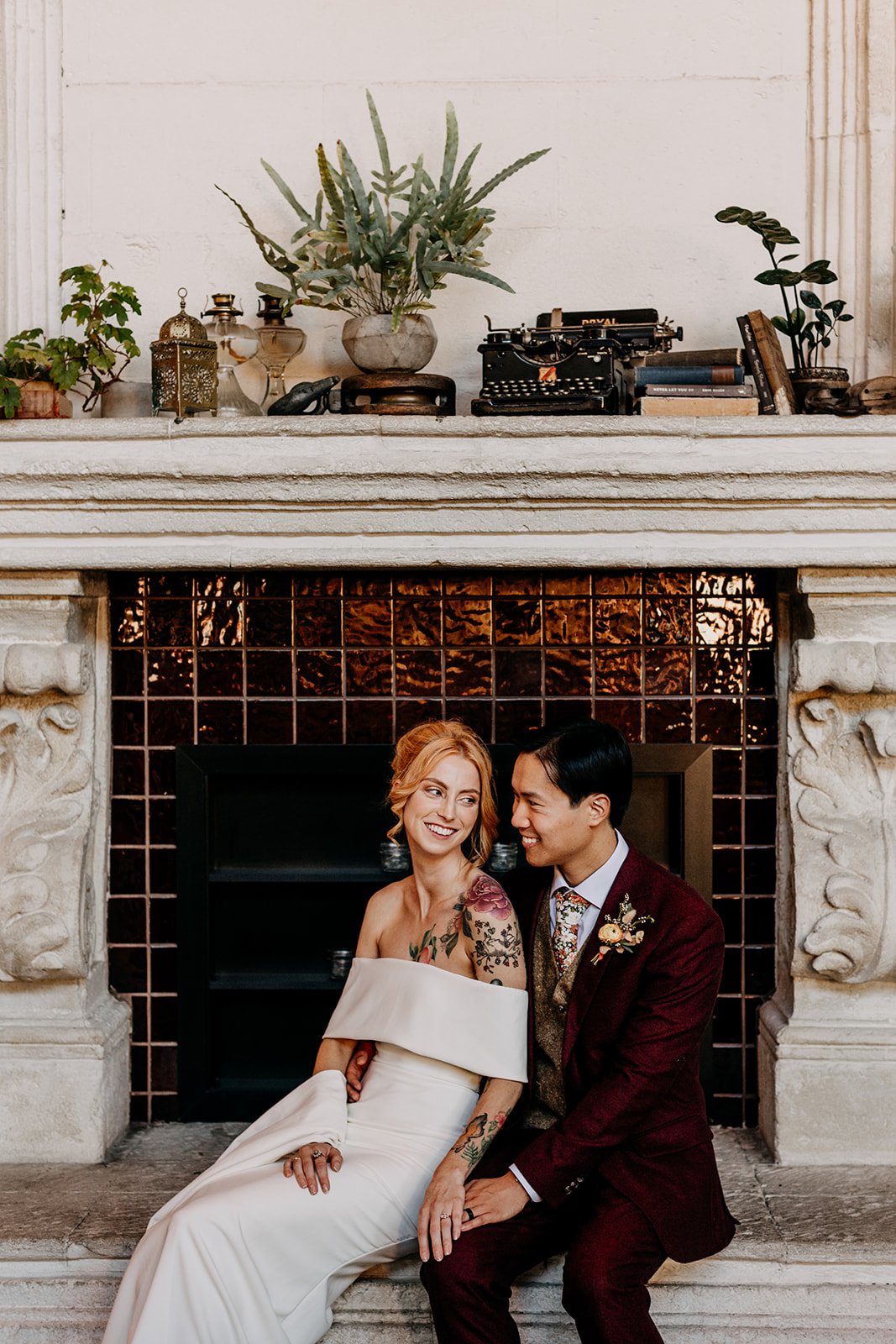 wedding couple sitting in front of fireplace inside Belgard Kitchen