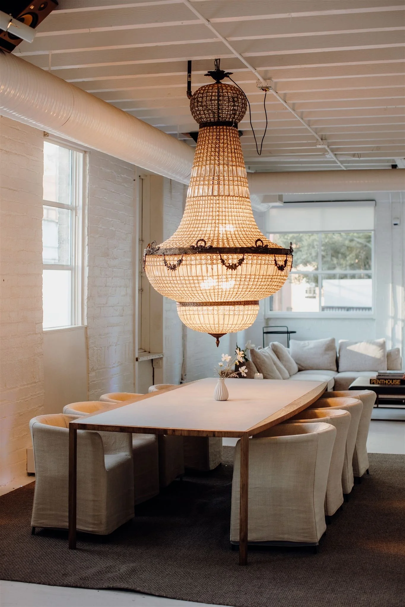 Large chandelier hangs above a table with comfy chairs inside The Kent in Vancouver
