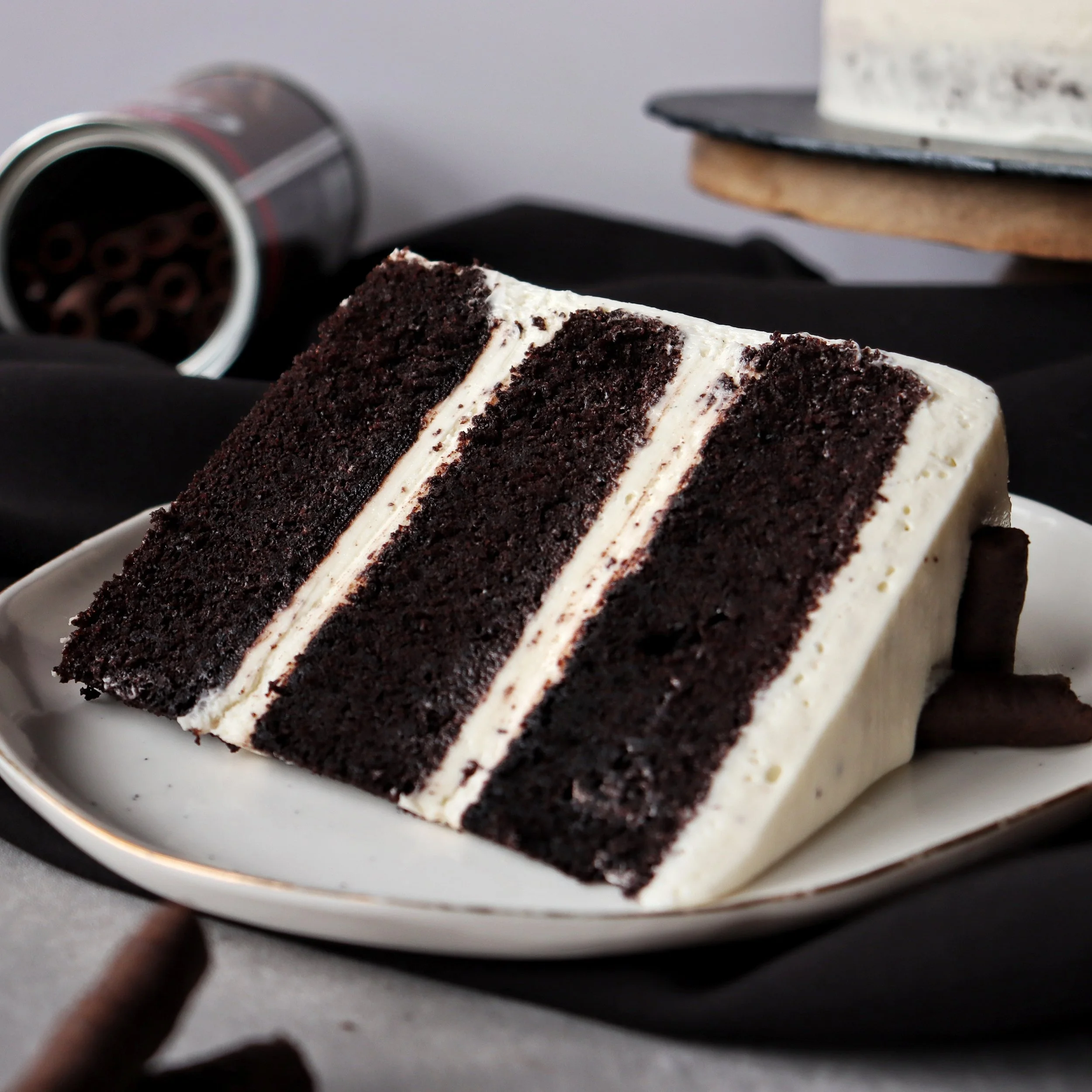 Slice of chocolate mayonnaise cake with white frosting on a white plate.