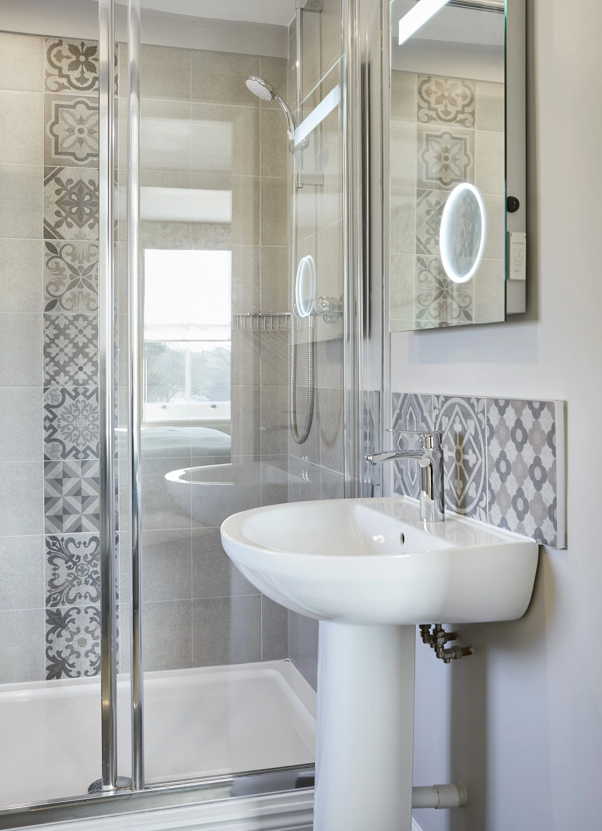 Modern bathroom with shower, tile patterns, and pedestal sink.