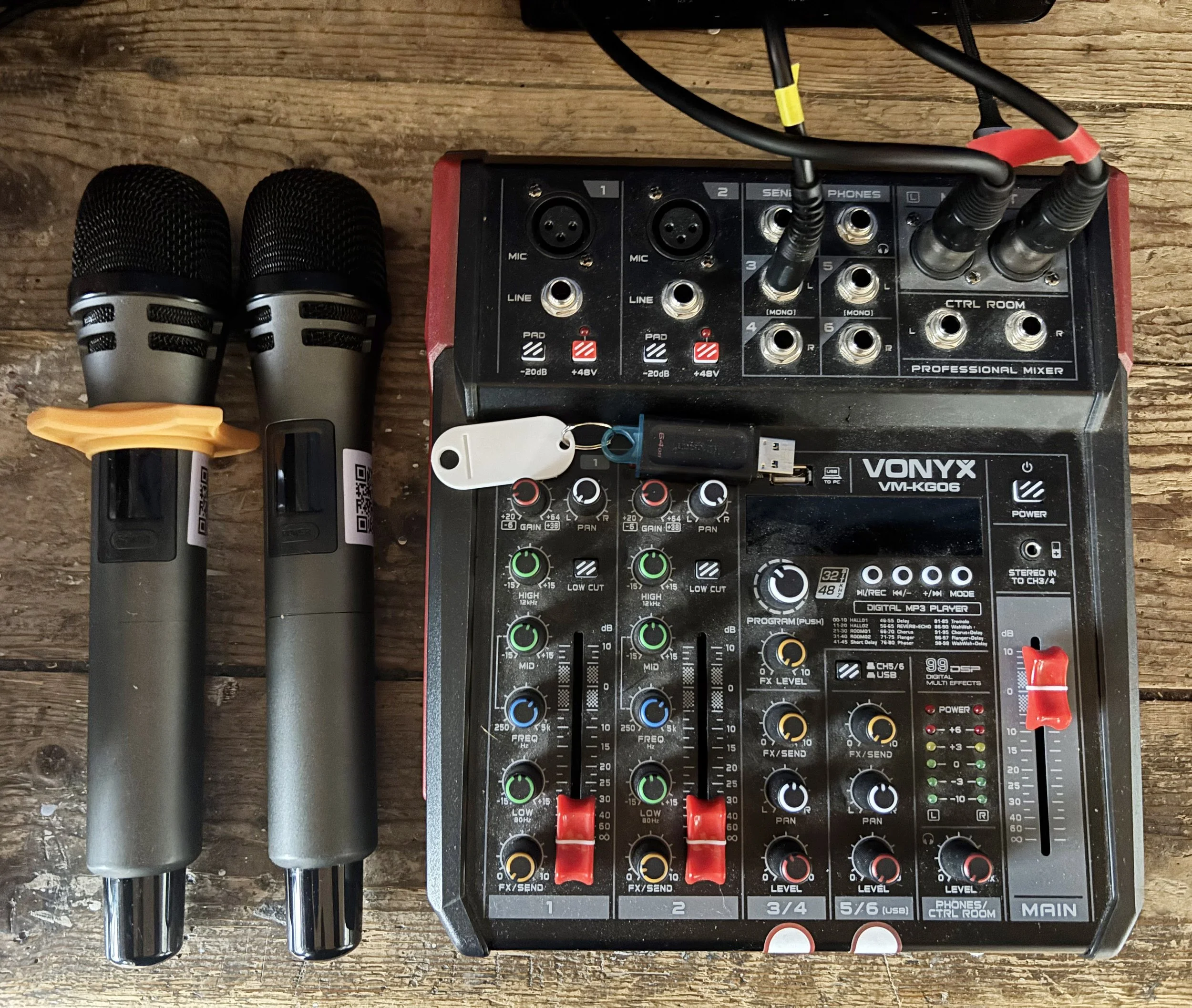 Music mixing equipment set up on a wooden table, including a rack-mounted mixer, a multi-channel controller, and a digital player.