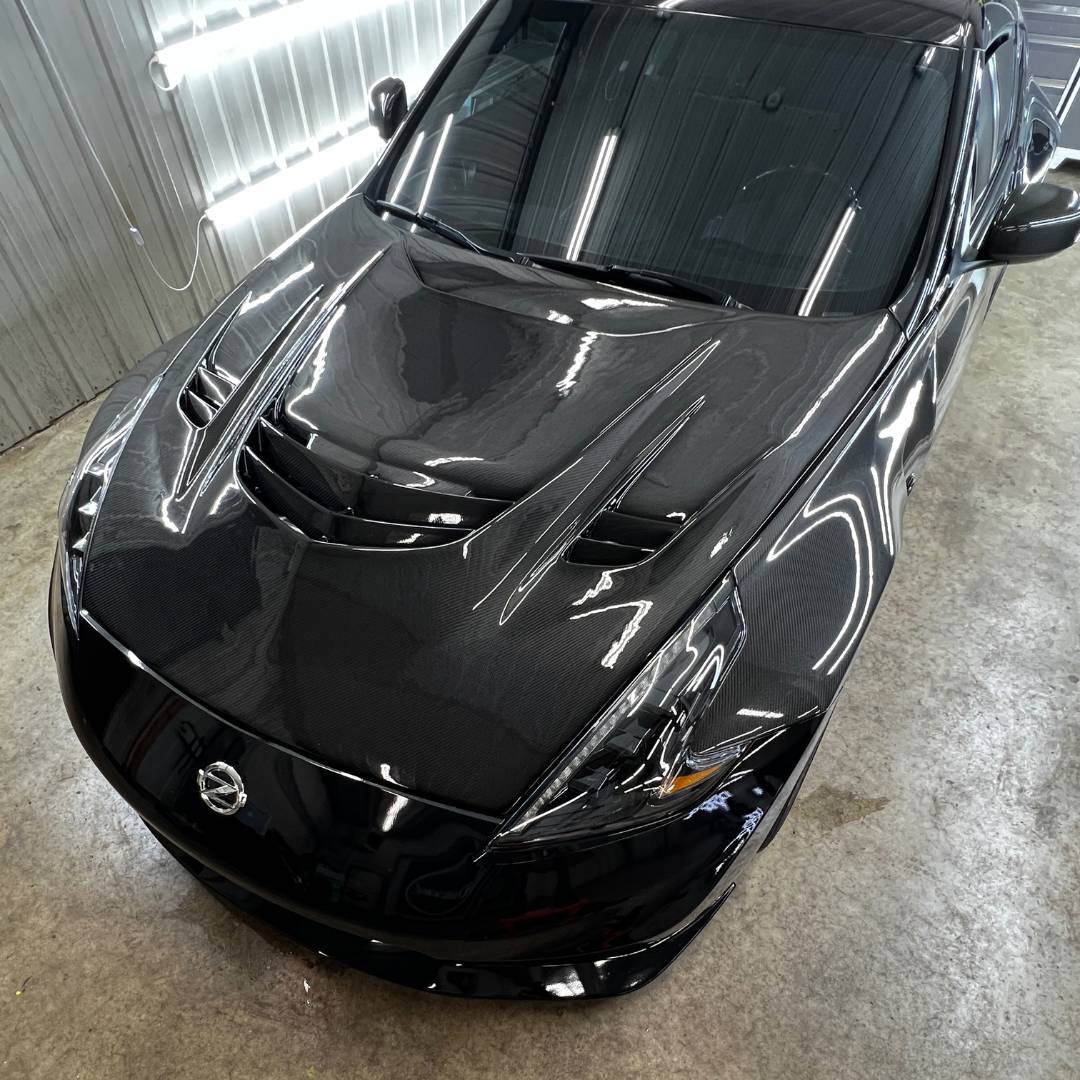 Black sports car with carbon fiber hood in a detail shop.