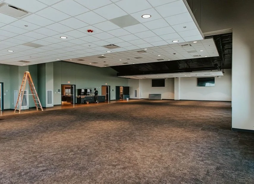 Person cleaning carpet with a vacuum cleaner in a living room, wearing blue disposable shoe covers and blue pants.