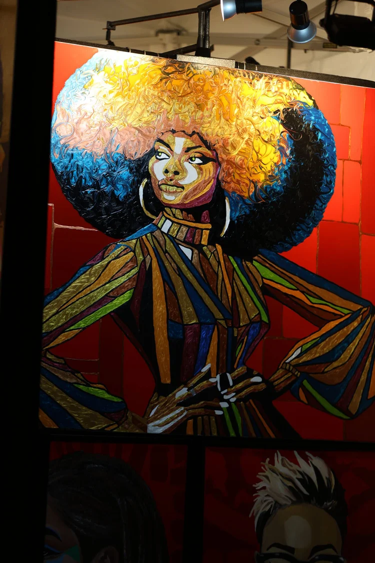 Bright portrait artwork displayed in an illuminated evening booth. 18th & Vine Arts Festival 2026.