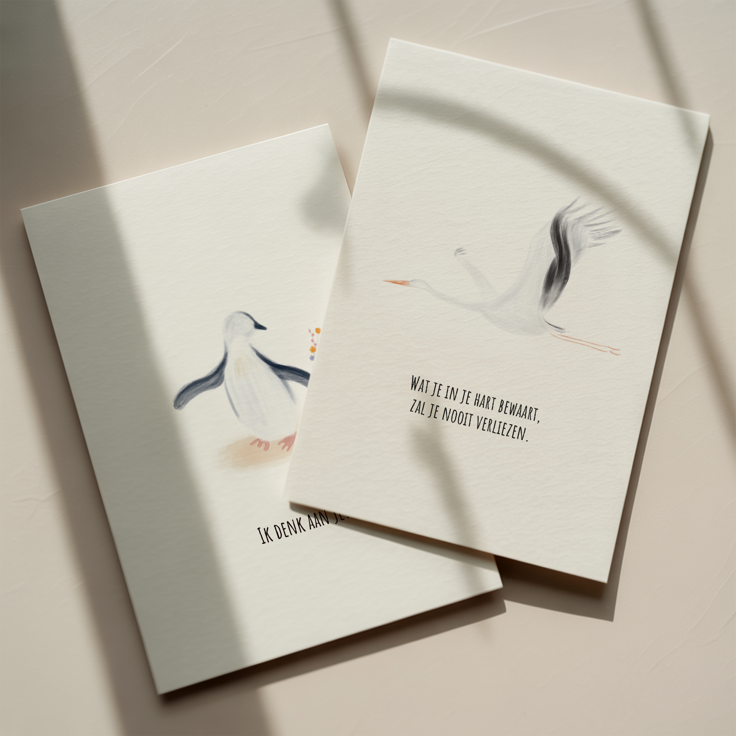 Twee kaarten met een kalligrafische illustratie van een zwaan en een citaat in het Nederlands, gelegen op een lichte achtergrond met schaduwen.