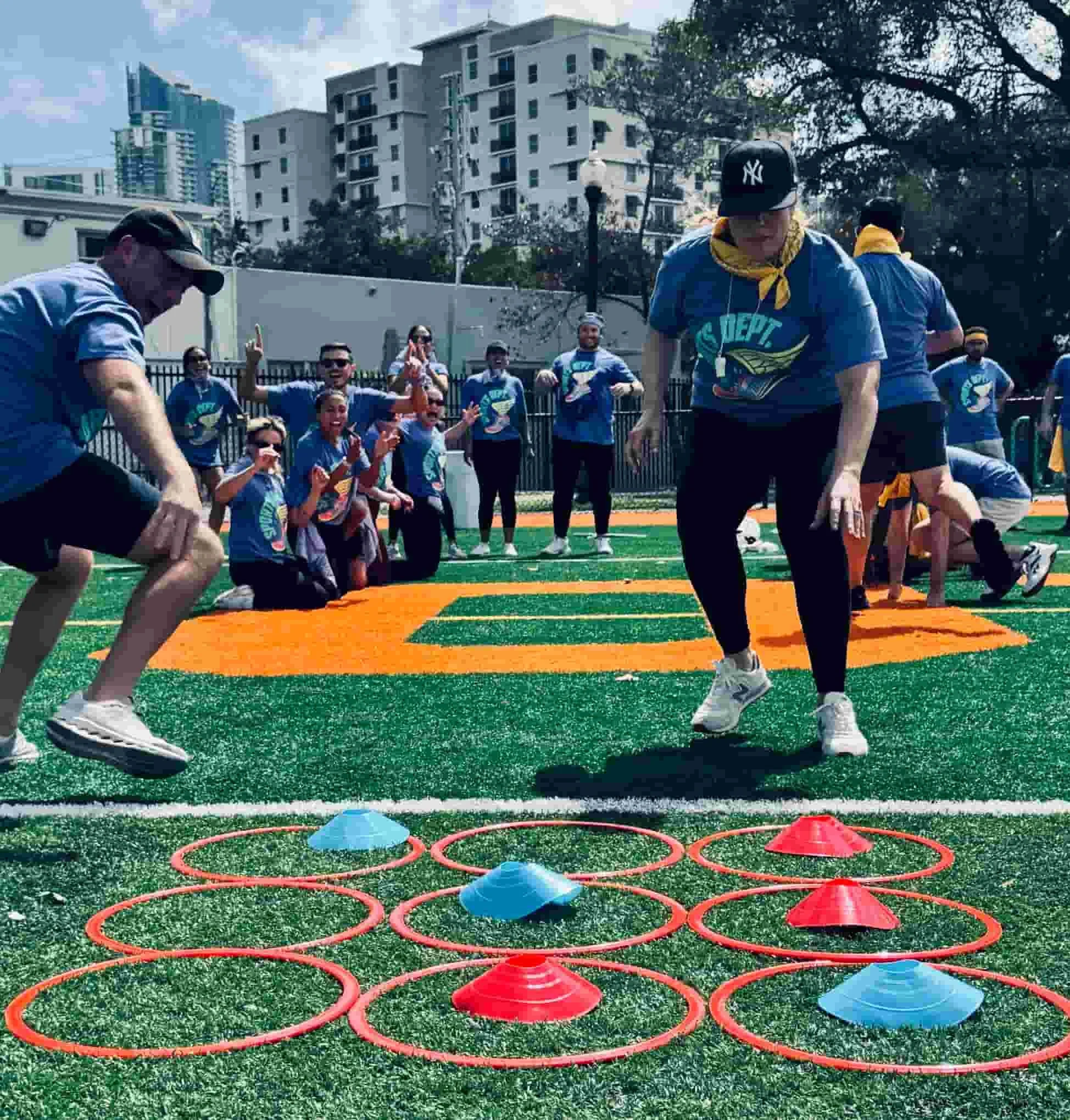 Team members racing through a tic-tac-toe relay game with agility hoops at a private group event