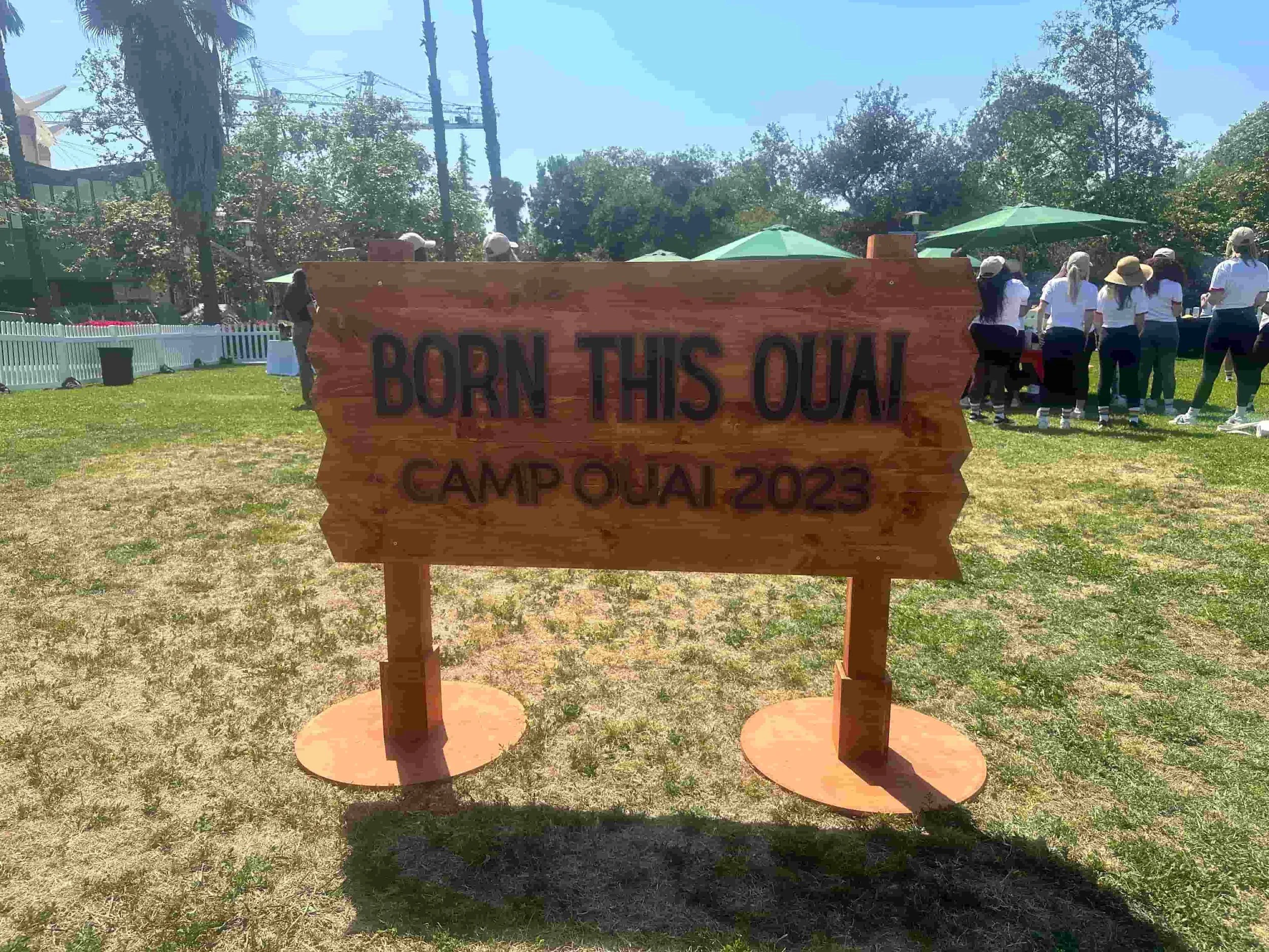 Custom wooden Camp Ouai 2023 sign reading Born This Ouai at an outdoor corporate team building event in Los Angeles