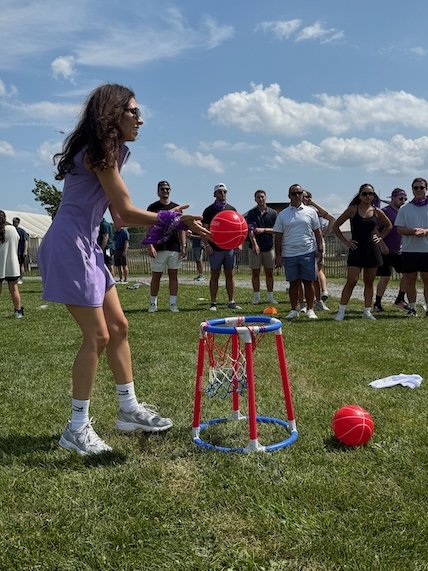 Adult players competing in a Hot Shots basketball-style game at a birthday party, a fun activity idea for adults