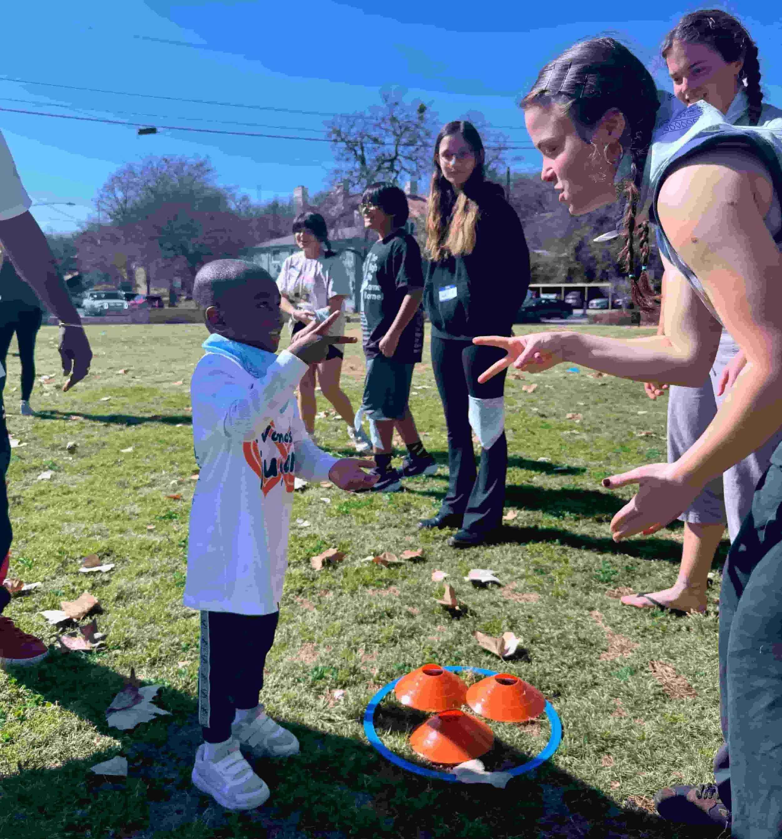 A young camper plays rock-paper-scissors with another camper at a field day for Experience Camps