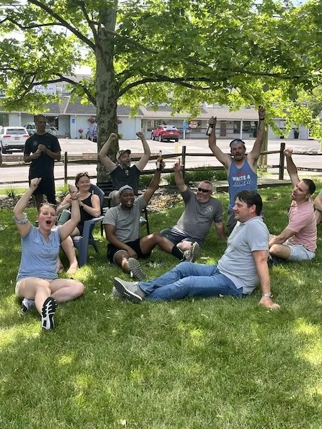 Group of adults celebrating outdoors during a Throwback team building field day event