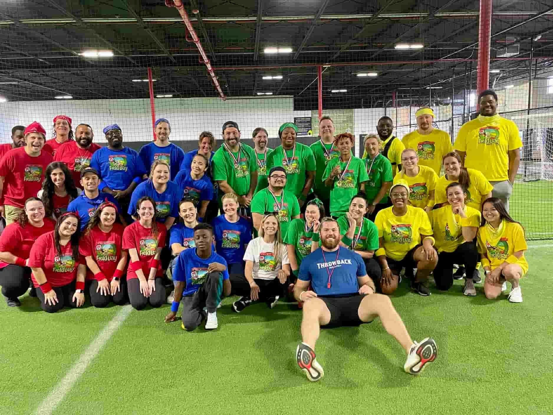 Large group of employees in team shirts posing after an indoor corporate team building field day in Miami