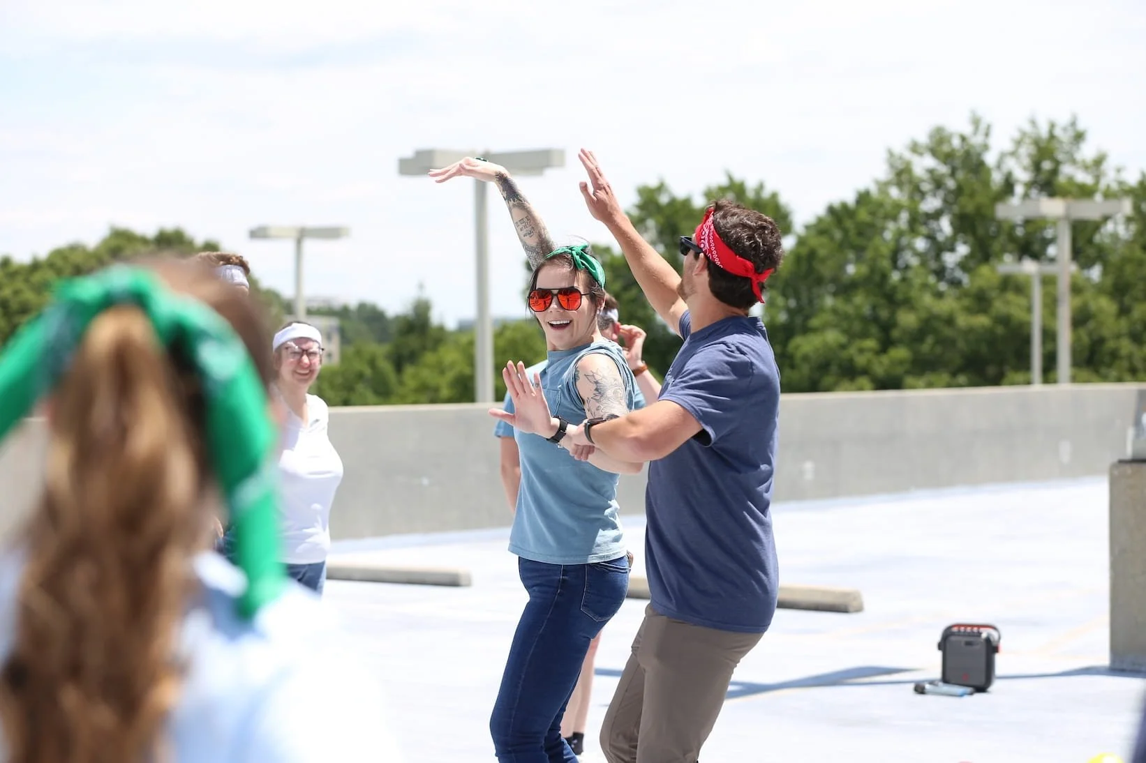 Two team members high-fiving in bandanas during a rooftop color war event in Atlanta