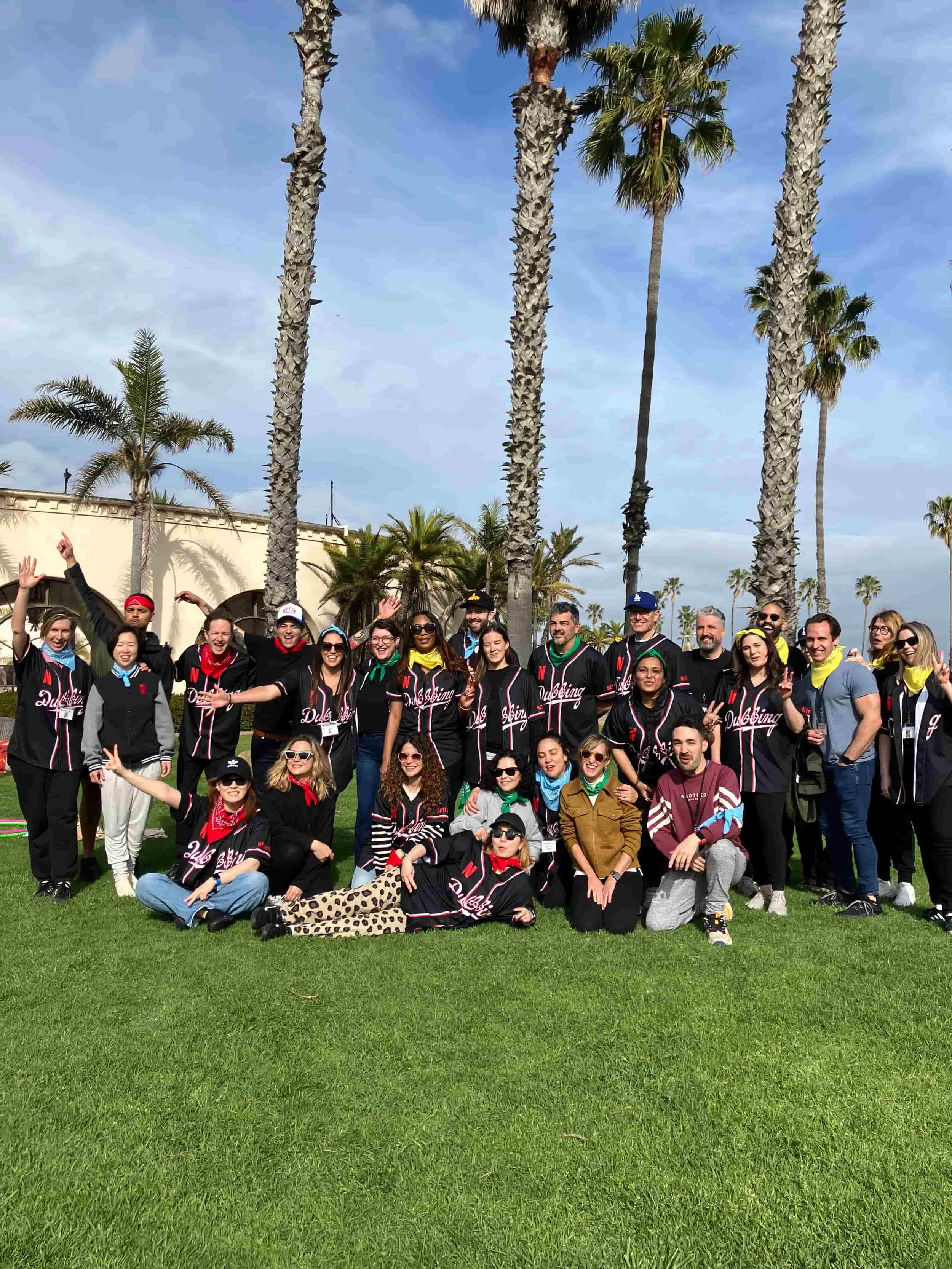 Corporate team in matching jerseys posing outdoors with palm trees during a team building event in Los Angeles