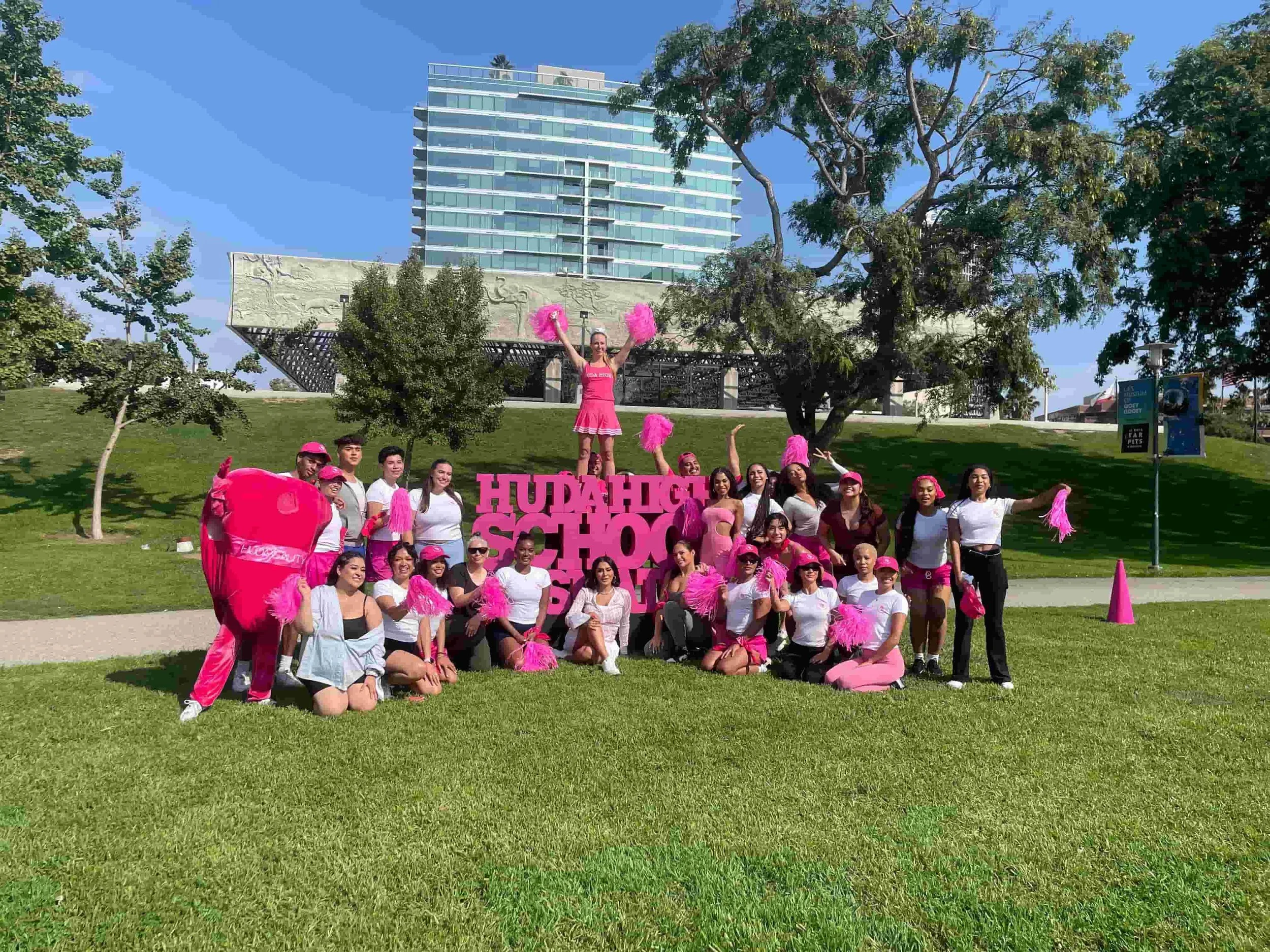 Huda Beauty employees in pink outfits and pompoms posing at a corporate team building field day in Los Angeles