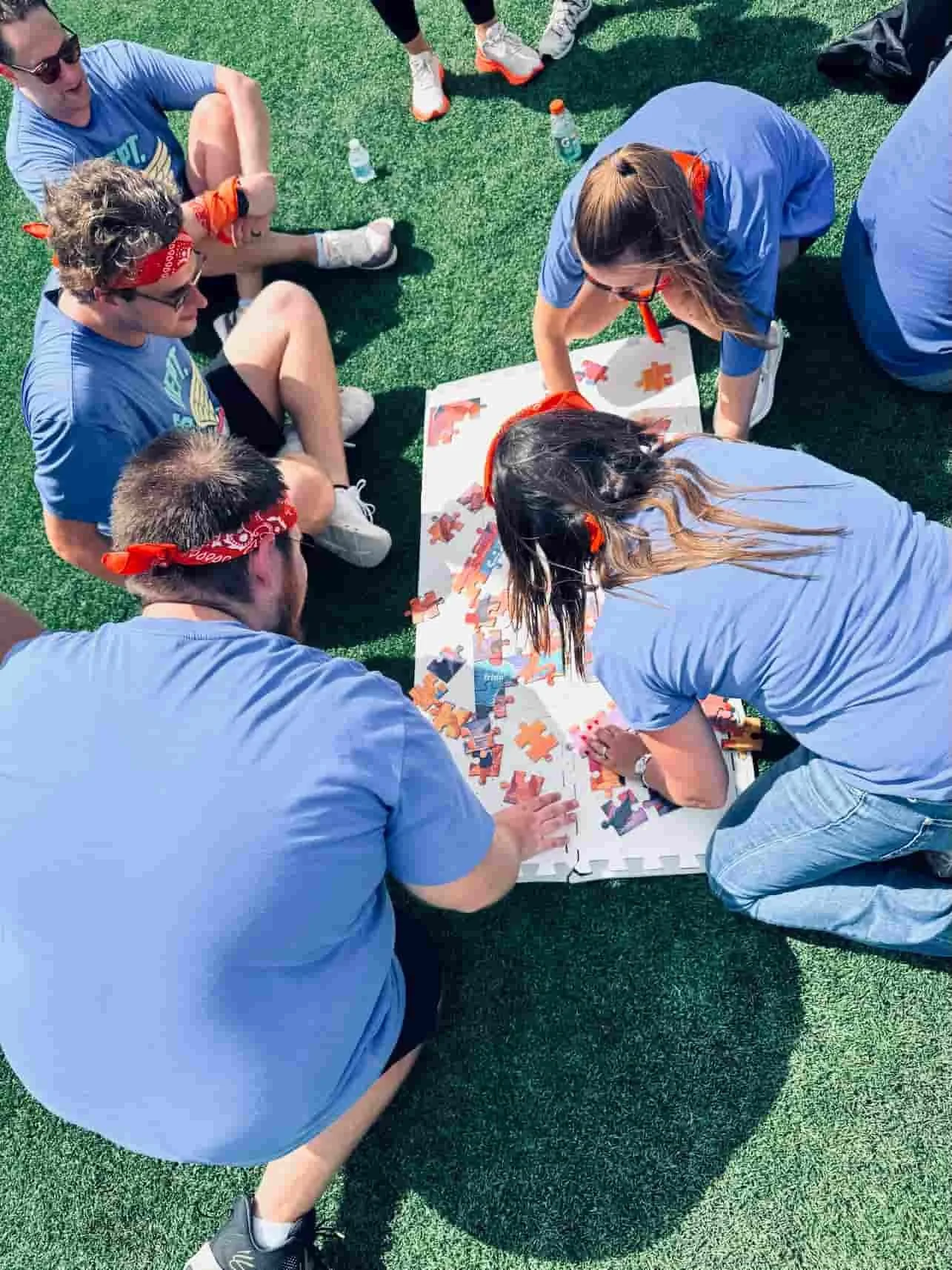 Corporate team working together on a large group puzzle activity during an outdoor field day in Miami