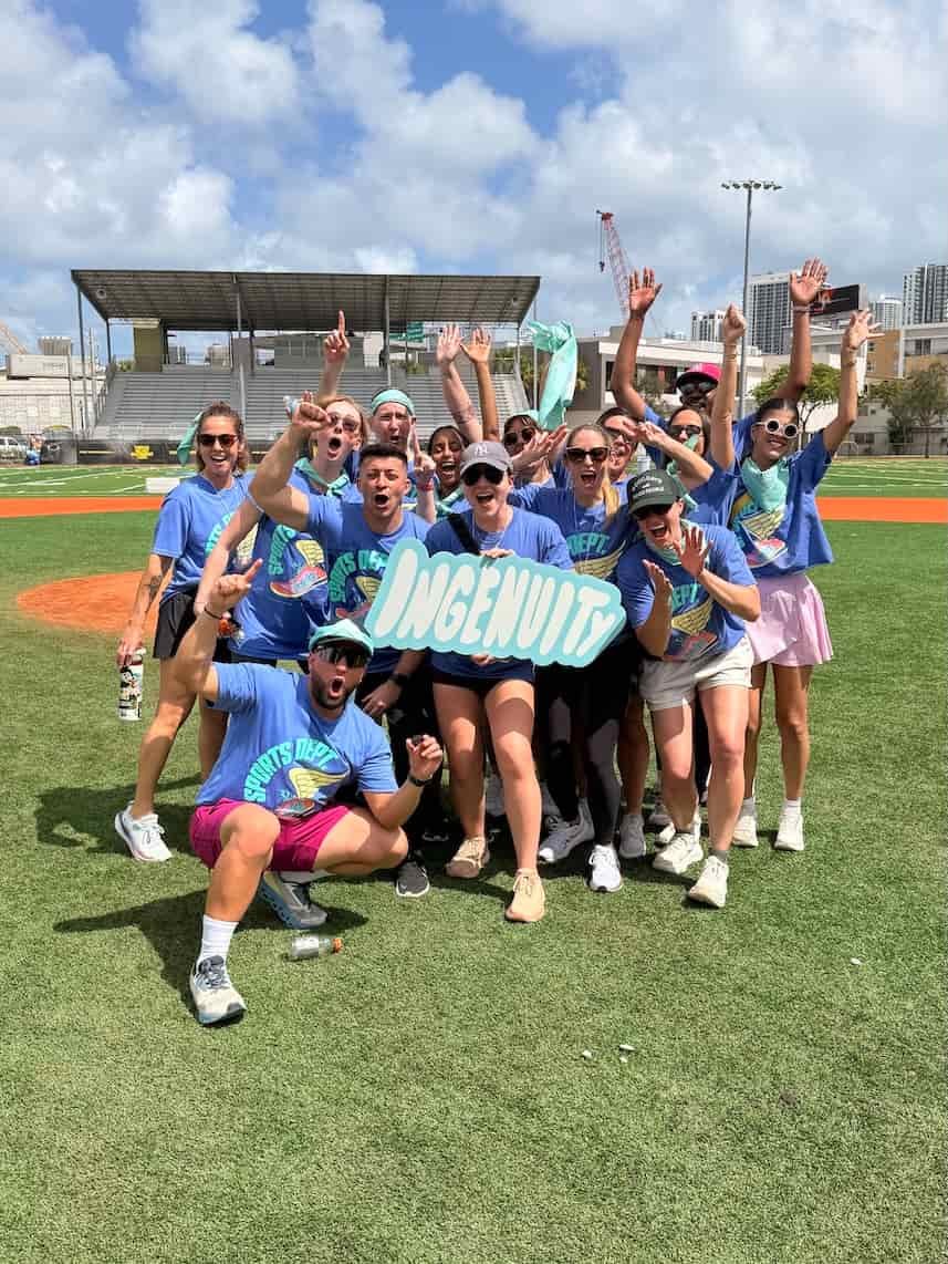 Corporate team building group celebrating at outdoor field day in Miami, wearing blue team shirts and holding a team sign