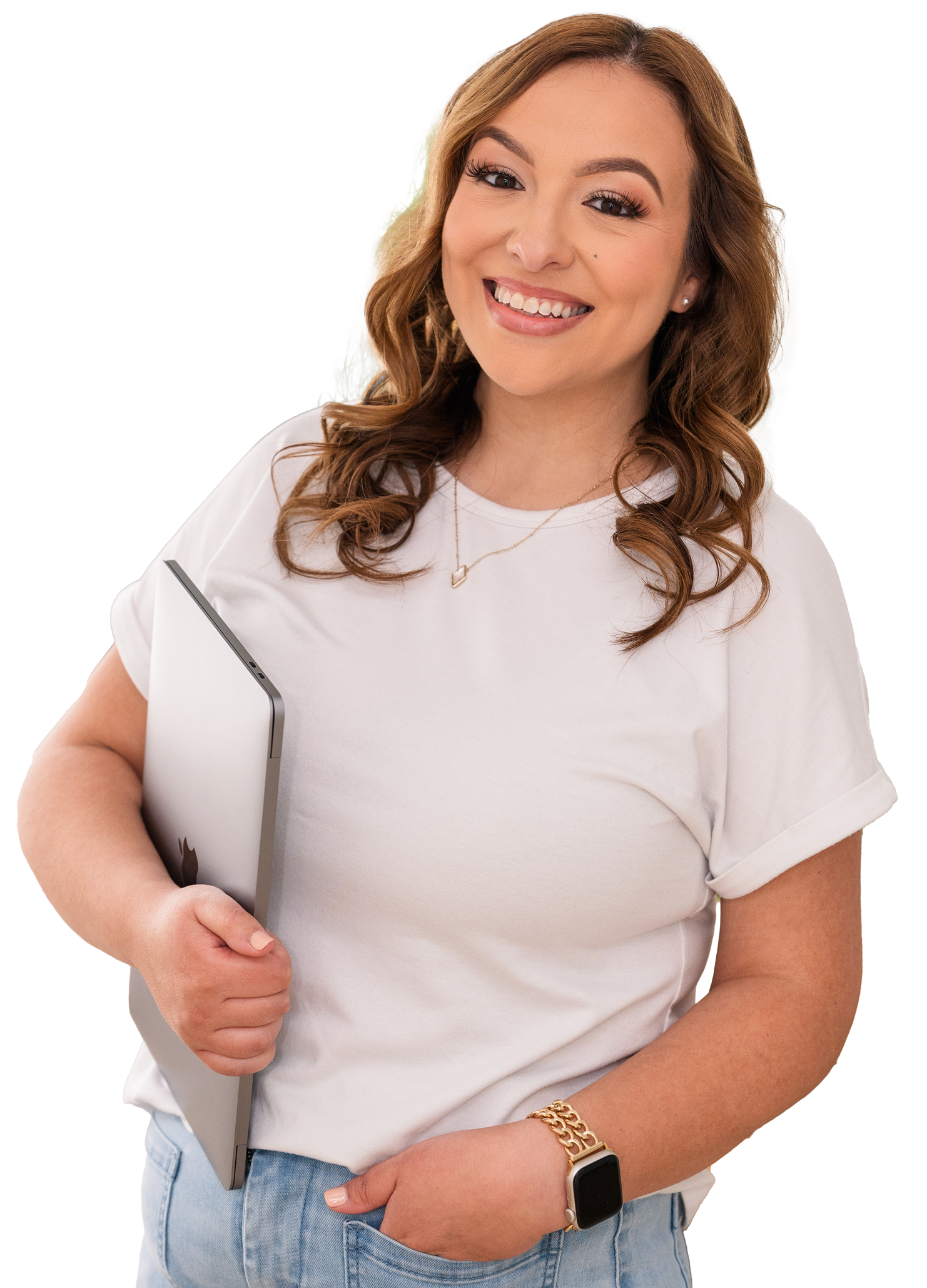A woman with wavy, shoulder-length hair and light skin smiling, holding a closed laptop under her arm, wearing a white t-shirt, light-wash jeans, a gold watch and bracelet, and a smartwatch.