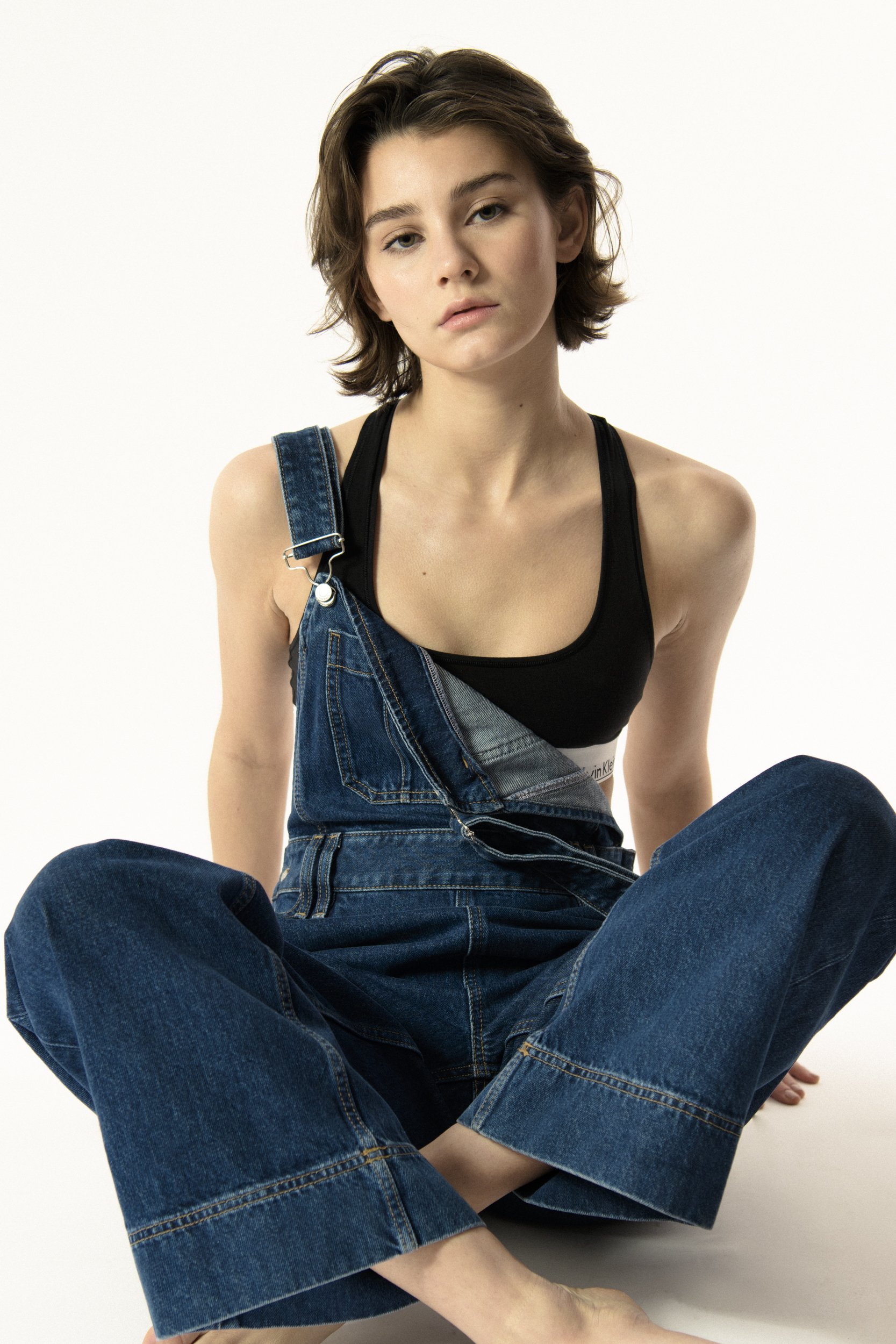 Model seating wearing jeans overalls