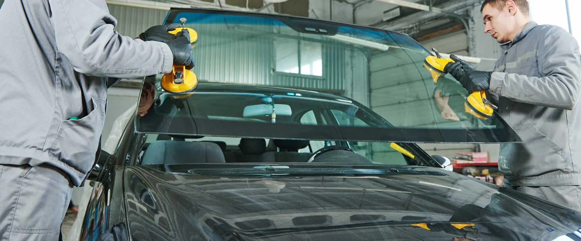 Two men replacing windshield in garage