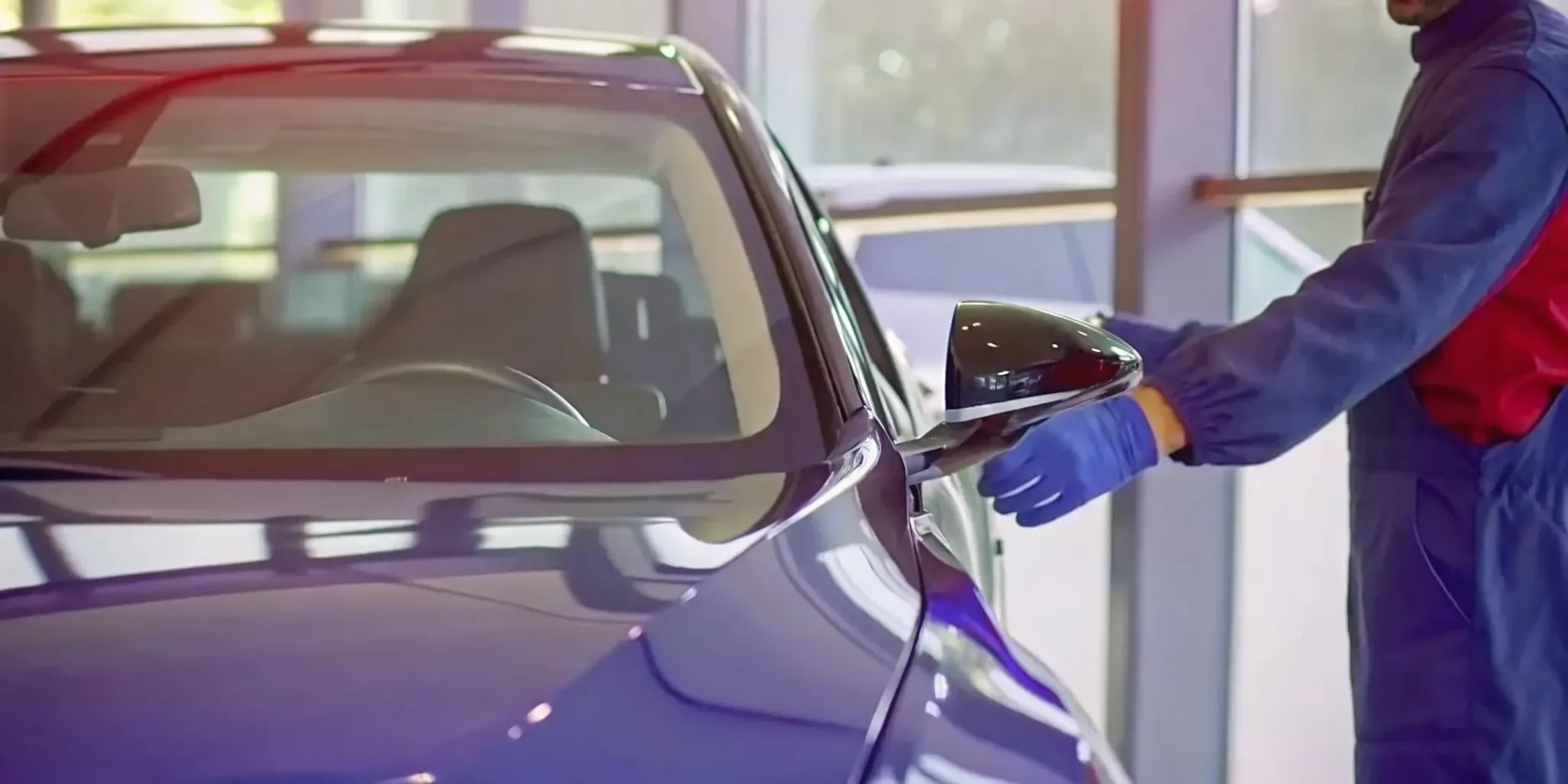Technician inspecting a cracked car windshield to determine the cost of a AAA replacement.
